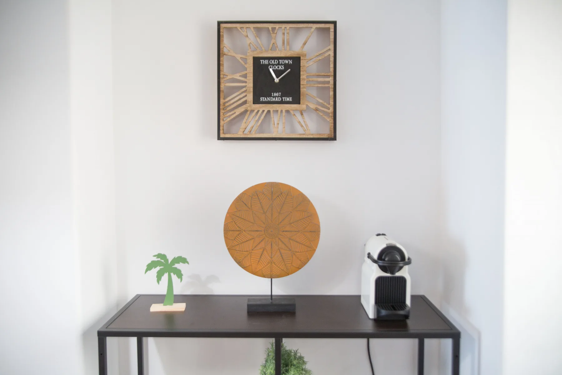 Una mesa consola exhibe una pieza decorativa redonda y una pequeña planta en maceta.