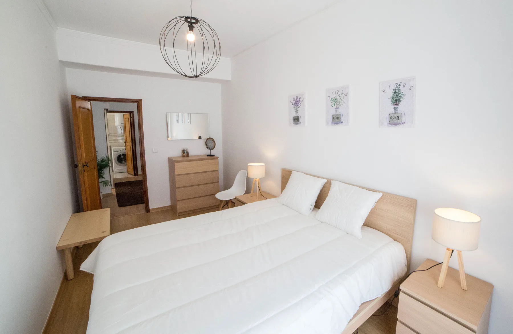 Un dormitorio luminoso con una cama doble, mesitas de noche y cuadros en la pared.