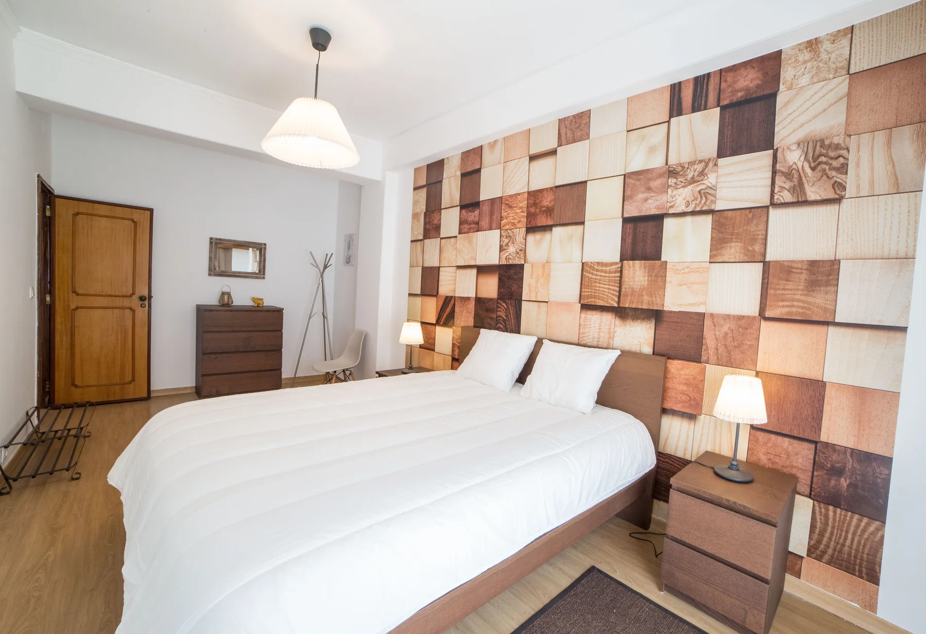 Un dormitorio con una cama grande y una pared de patrón geométrico detrás.