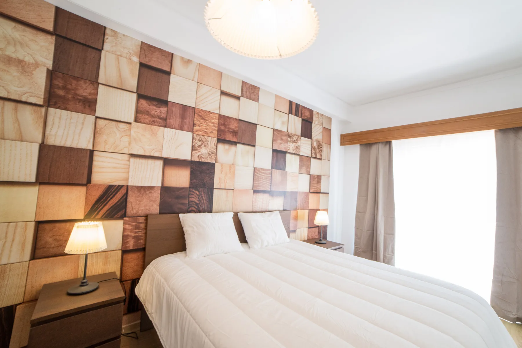 Un dormitorio con una cama junto a una ventana y paneles decorativos en la pared.