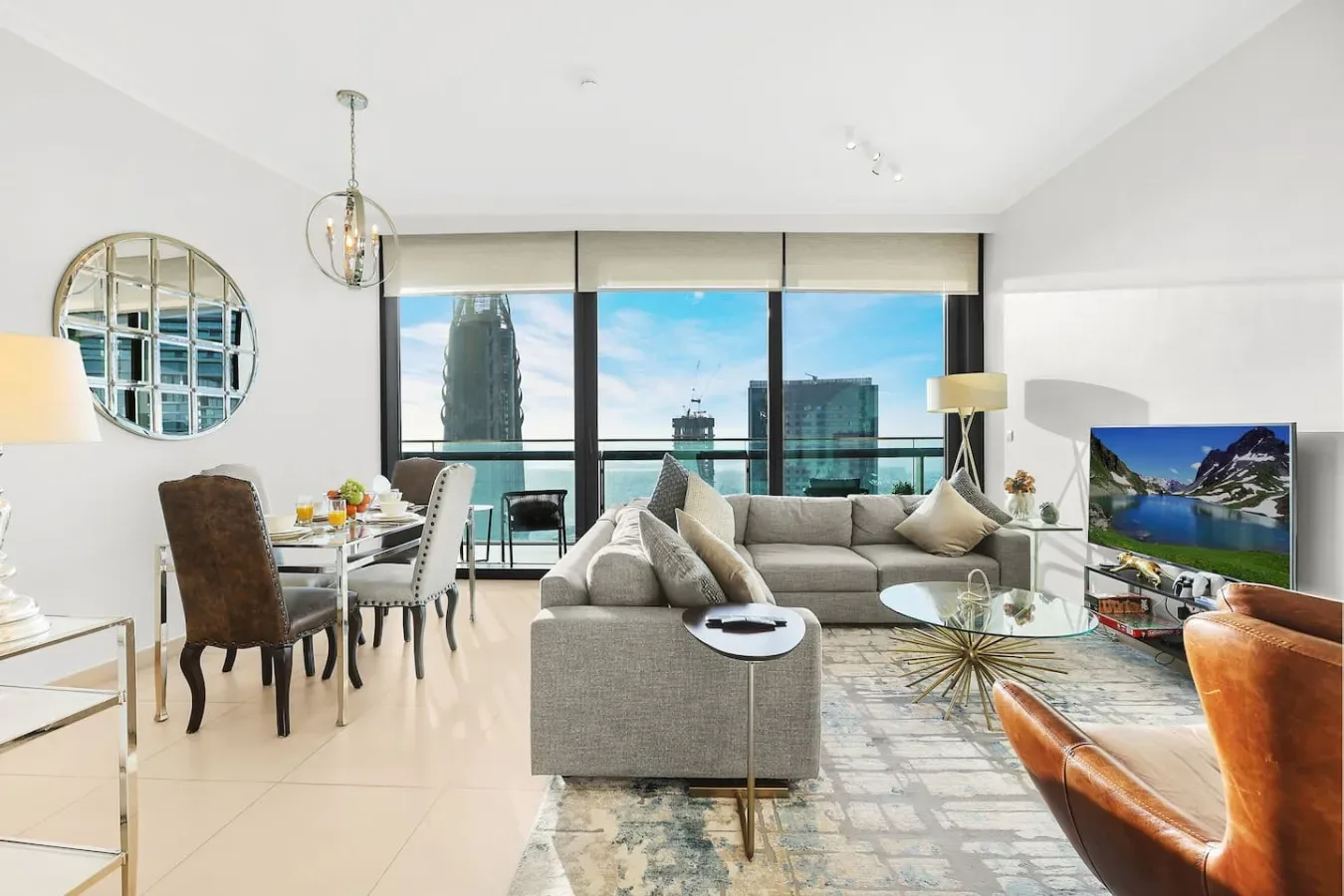 A bright living and dining area opens onto large windows overlooking nearby buildings.