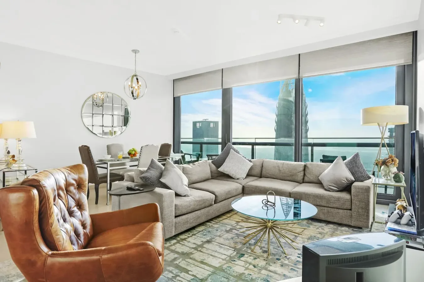 A bright living room with sectional seating and large windows overlooking the water.