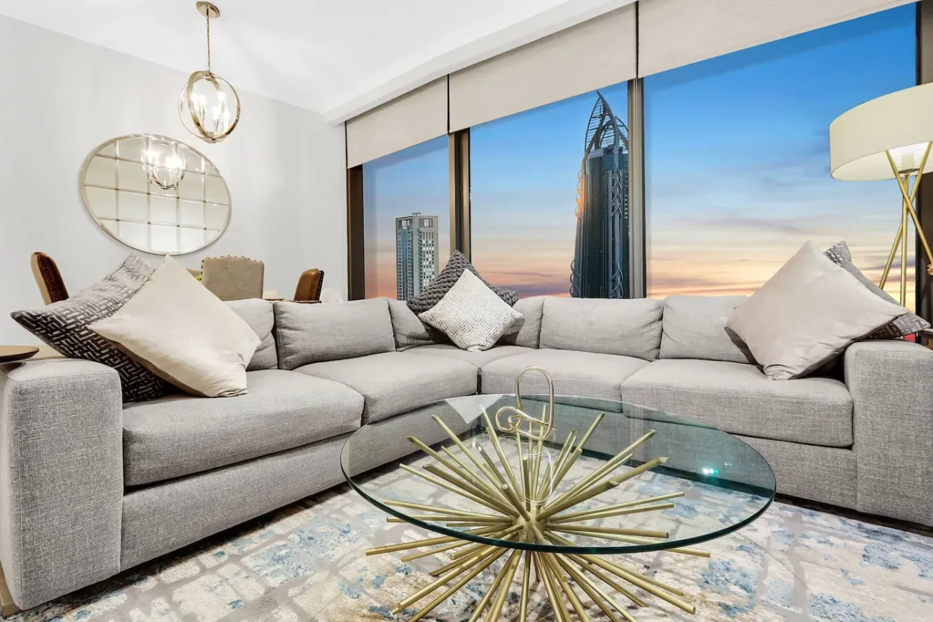 A living room with a large gray sectional facing floor-to-ceiling windows.