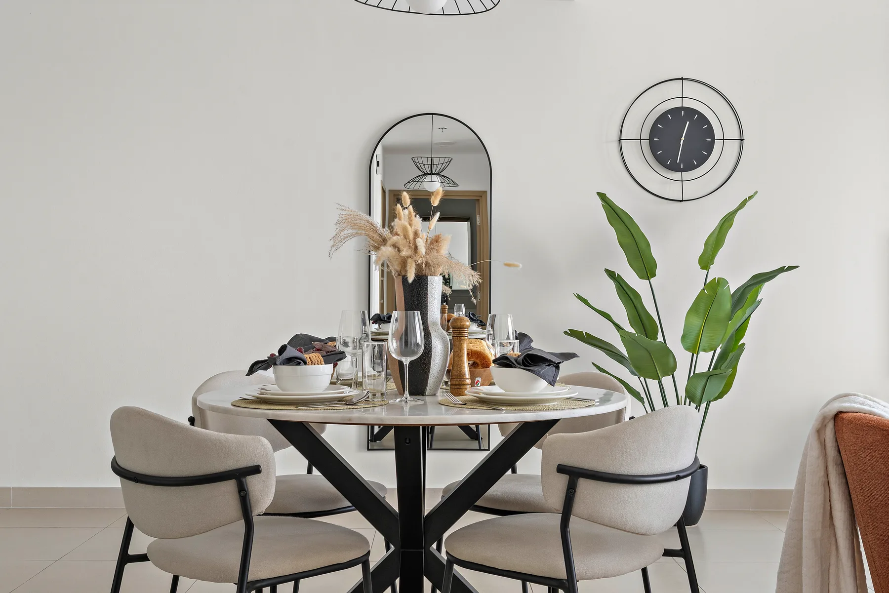 Un comedor con una mesa puesta, asientos tapizados y una planta en maceta.