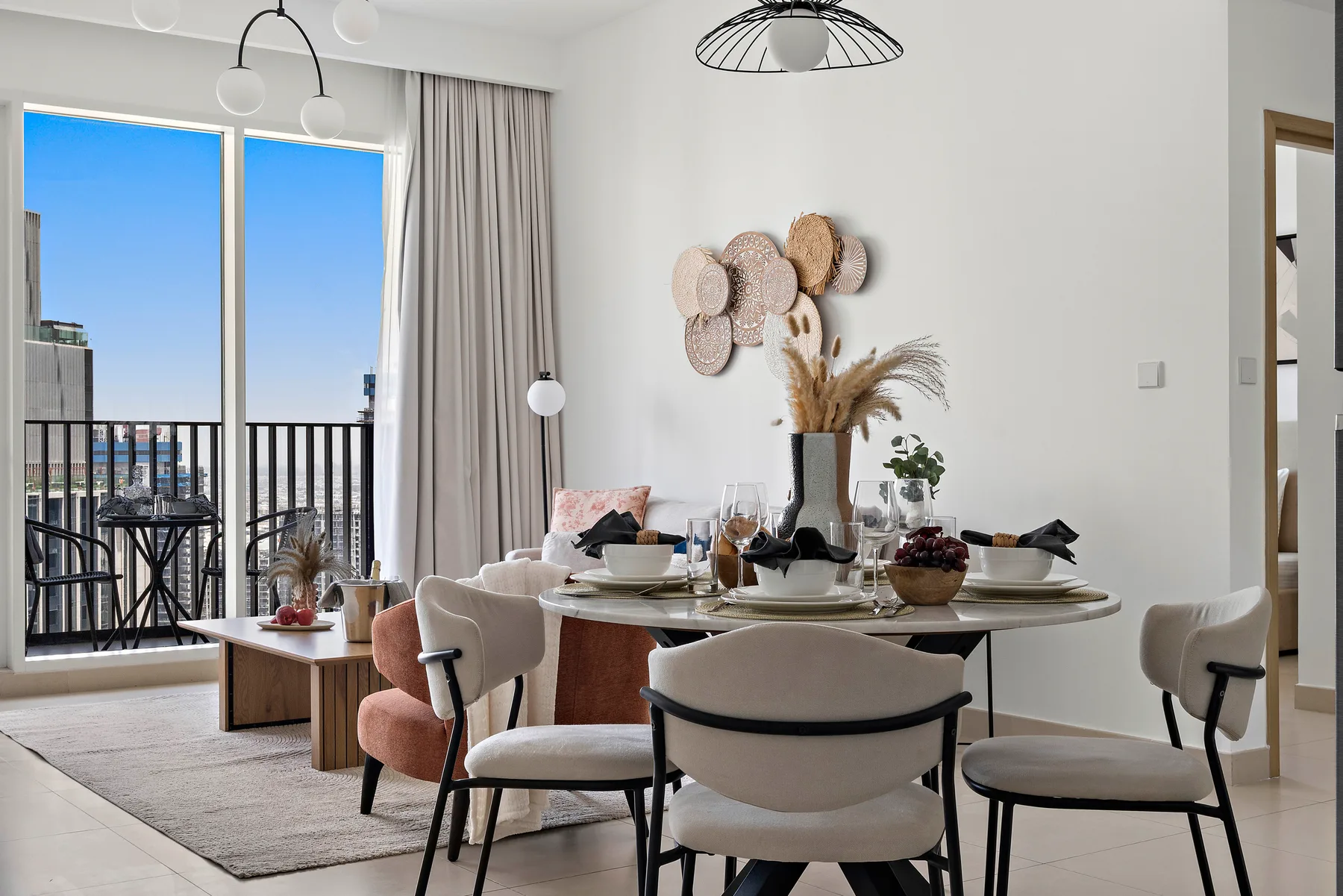 Un comedor luminoso con la mesa puesta junto a grandes ventanales que dan a un balcón.