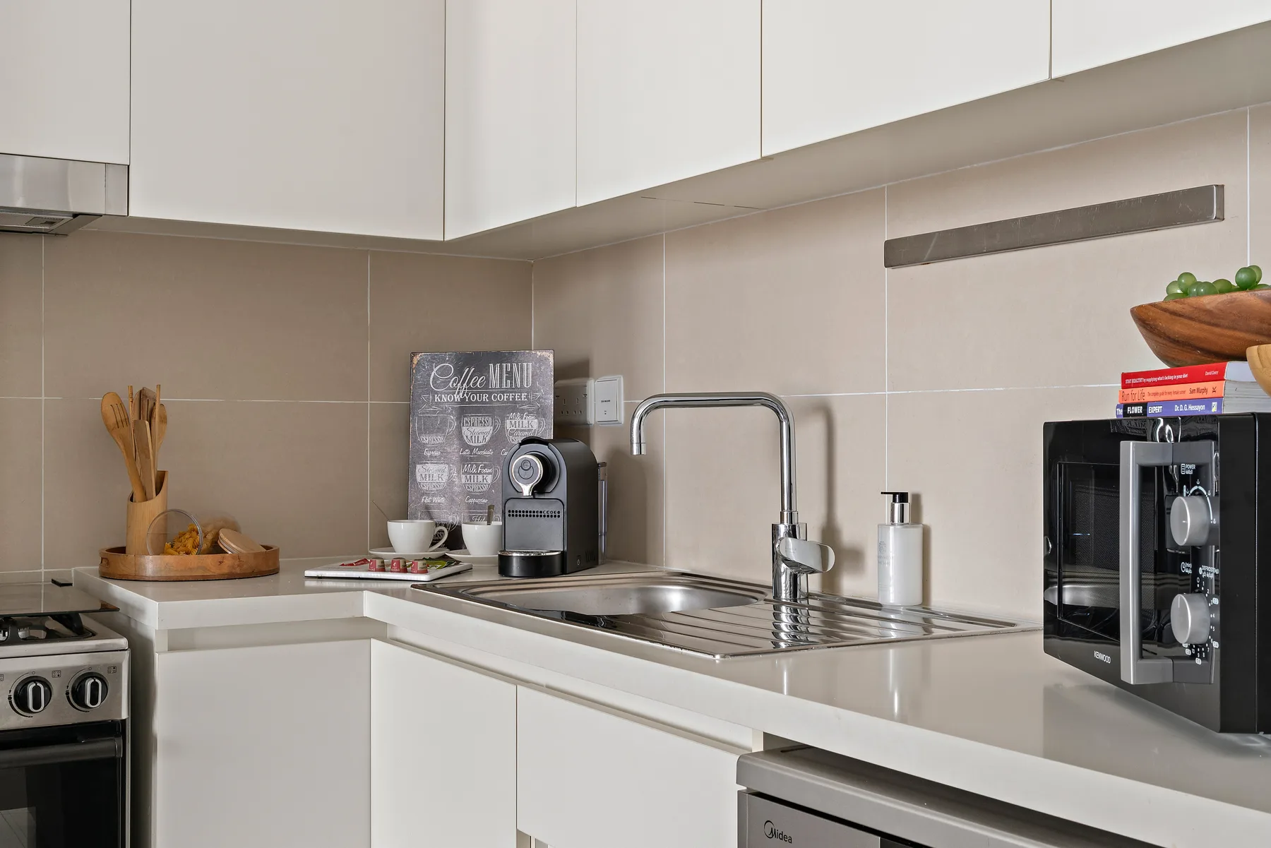 Una cocina moderna con fregadero, pequeños electrodomésticos y armarios blancos.