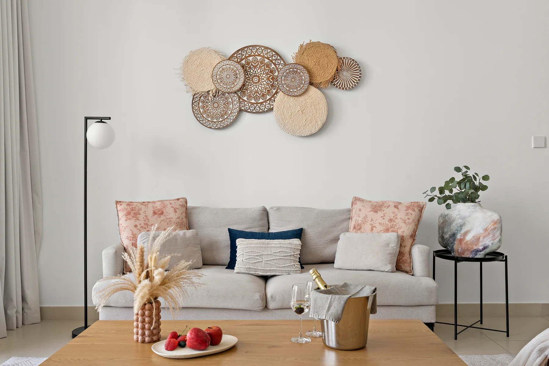 Una sala luminosa con un sofá claro, arte decorativo en la pared y una mesa de centro.