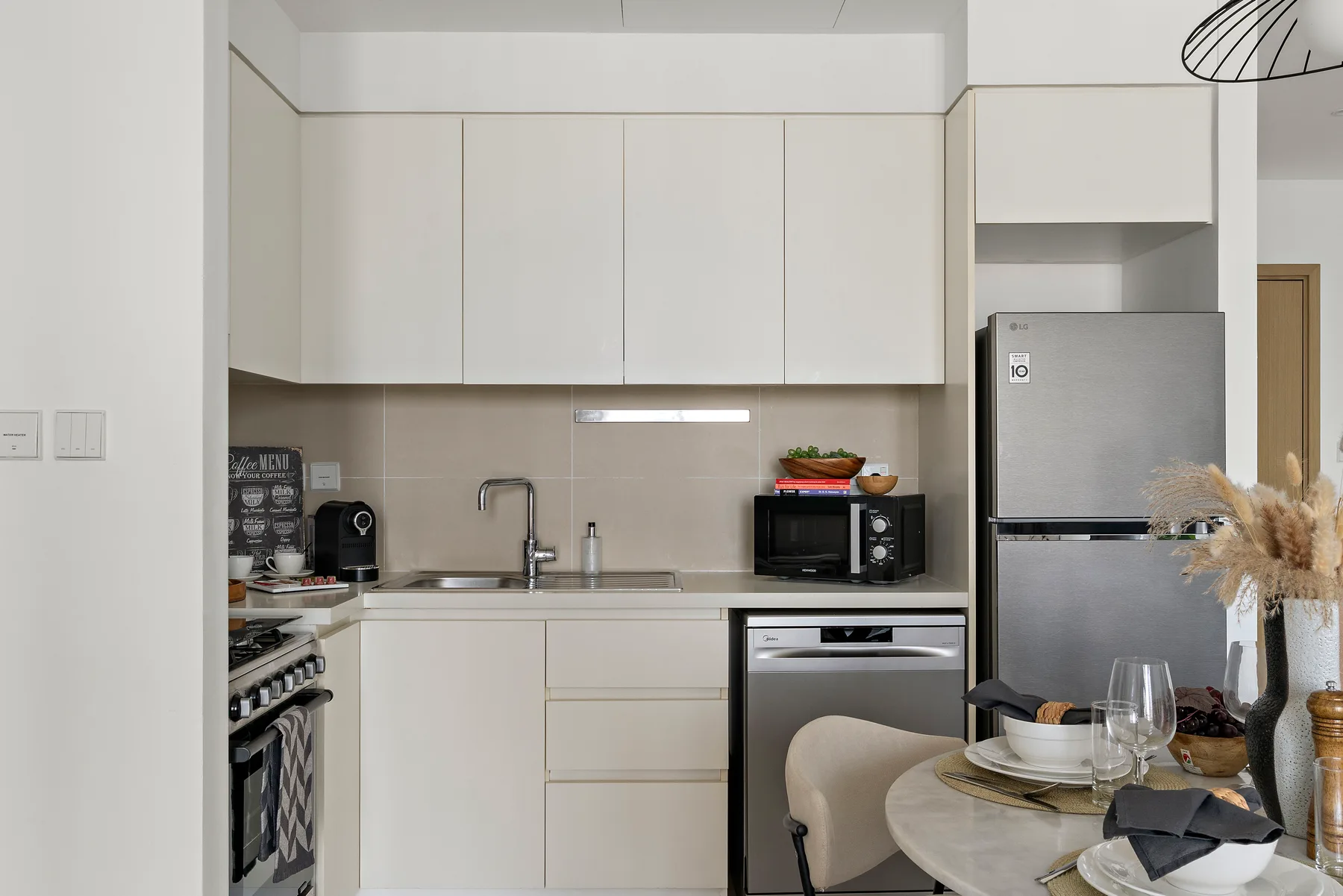 Una cocina moderna con gabinetes blancos, electrodomésticos de acero inoxidable y una mesa de comedor.