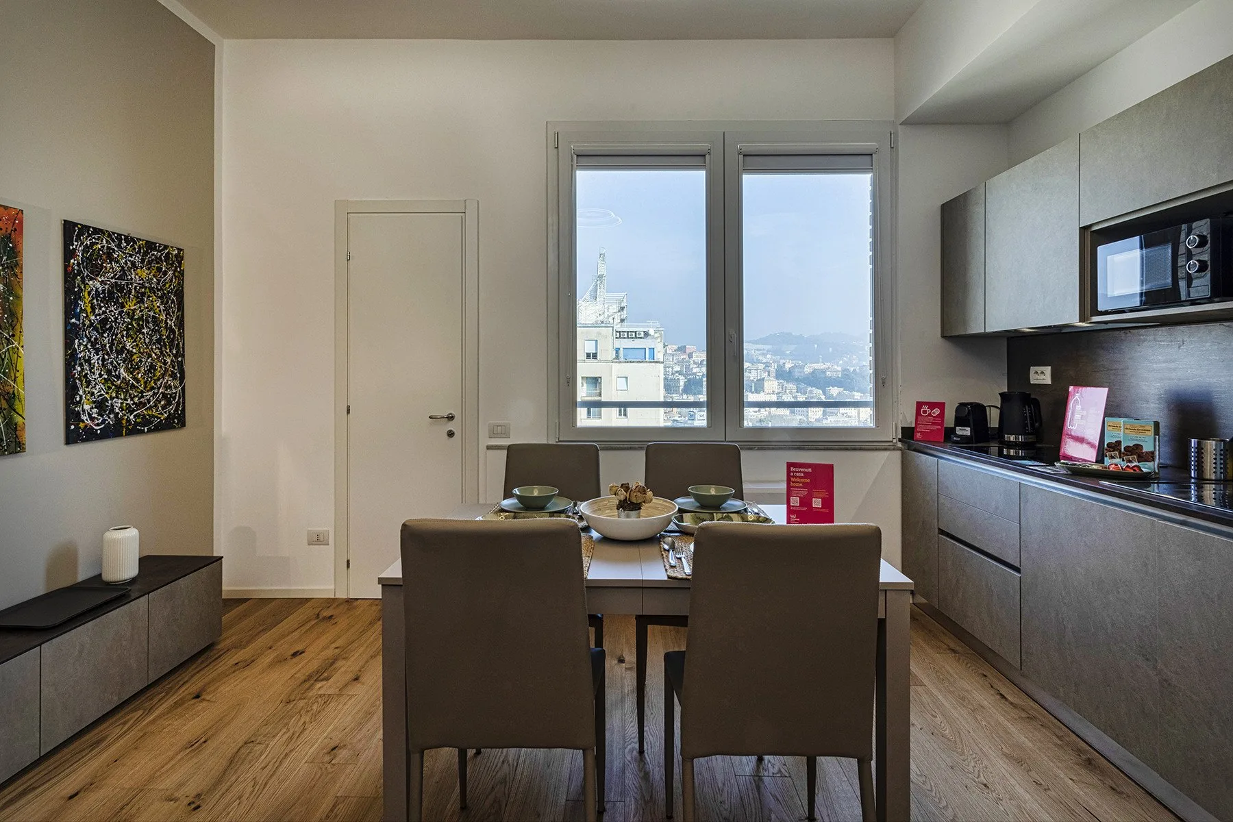 A dining area with a table and chairs beside a kitchen counter and windows.