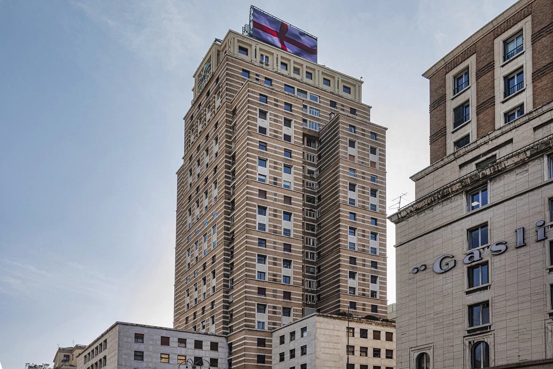 A tall multi-story building with rows of windows stands against the sky.