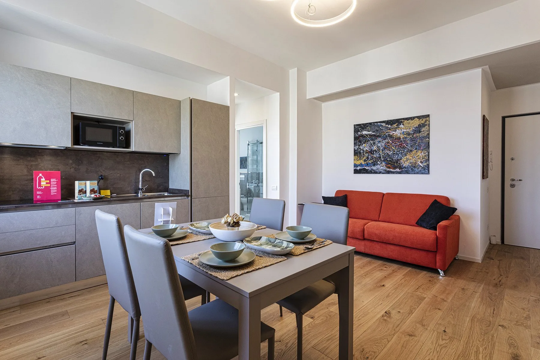 An open-plan dining and living area has a table beside a red sofa.