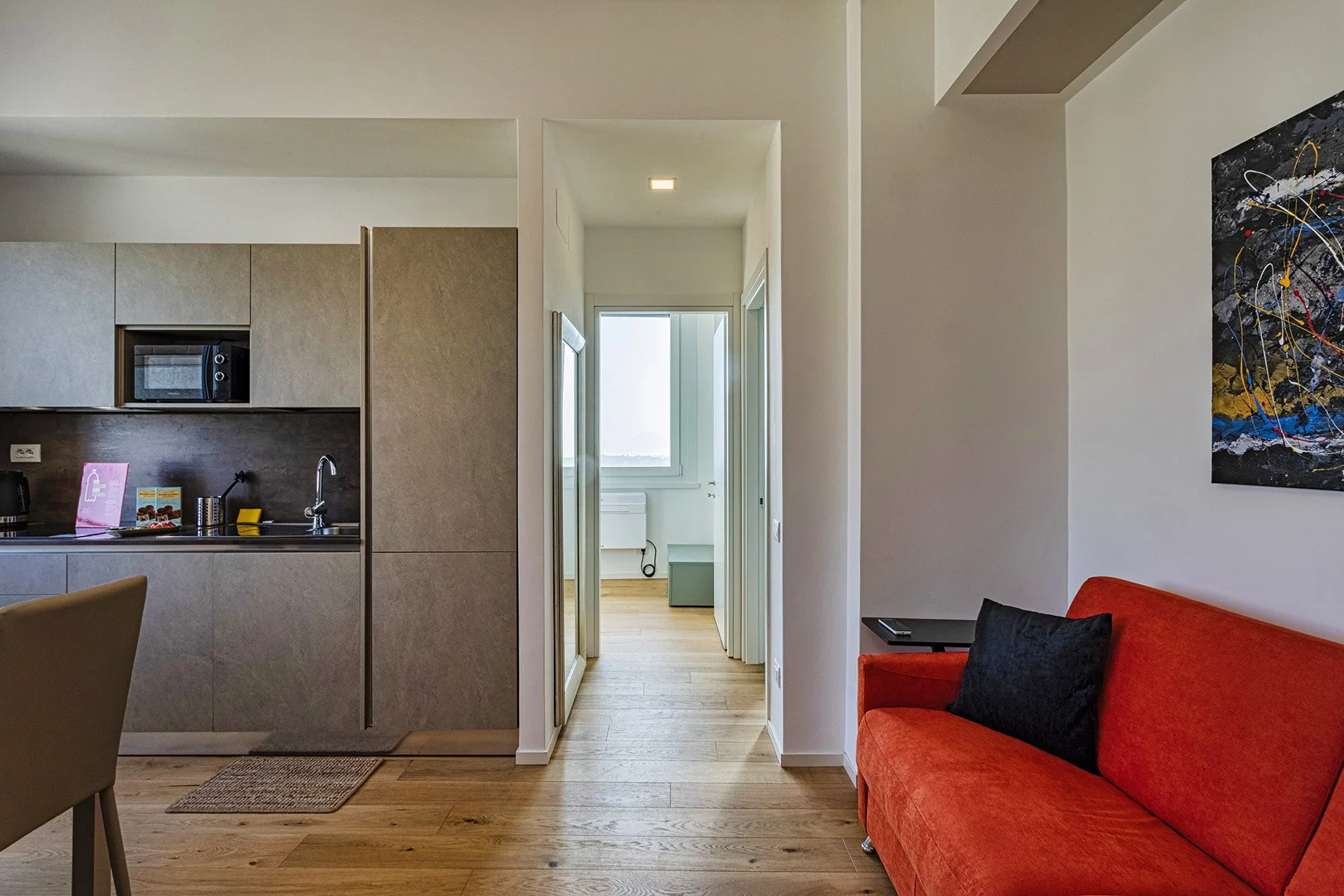 A living area with an orange sofa beside a compact kitchen.