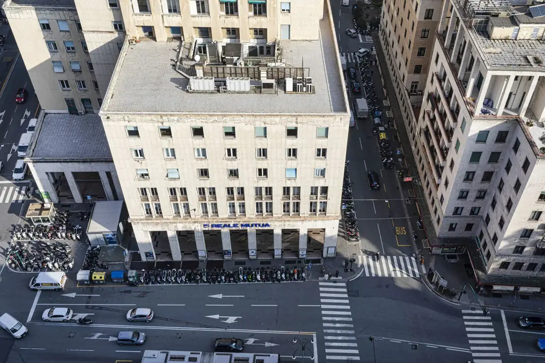 An aerial view of a city street lined with buildings and parked vehicles.