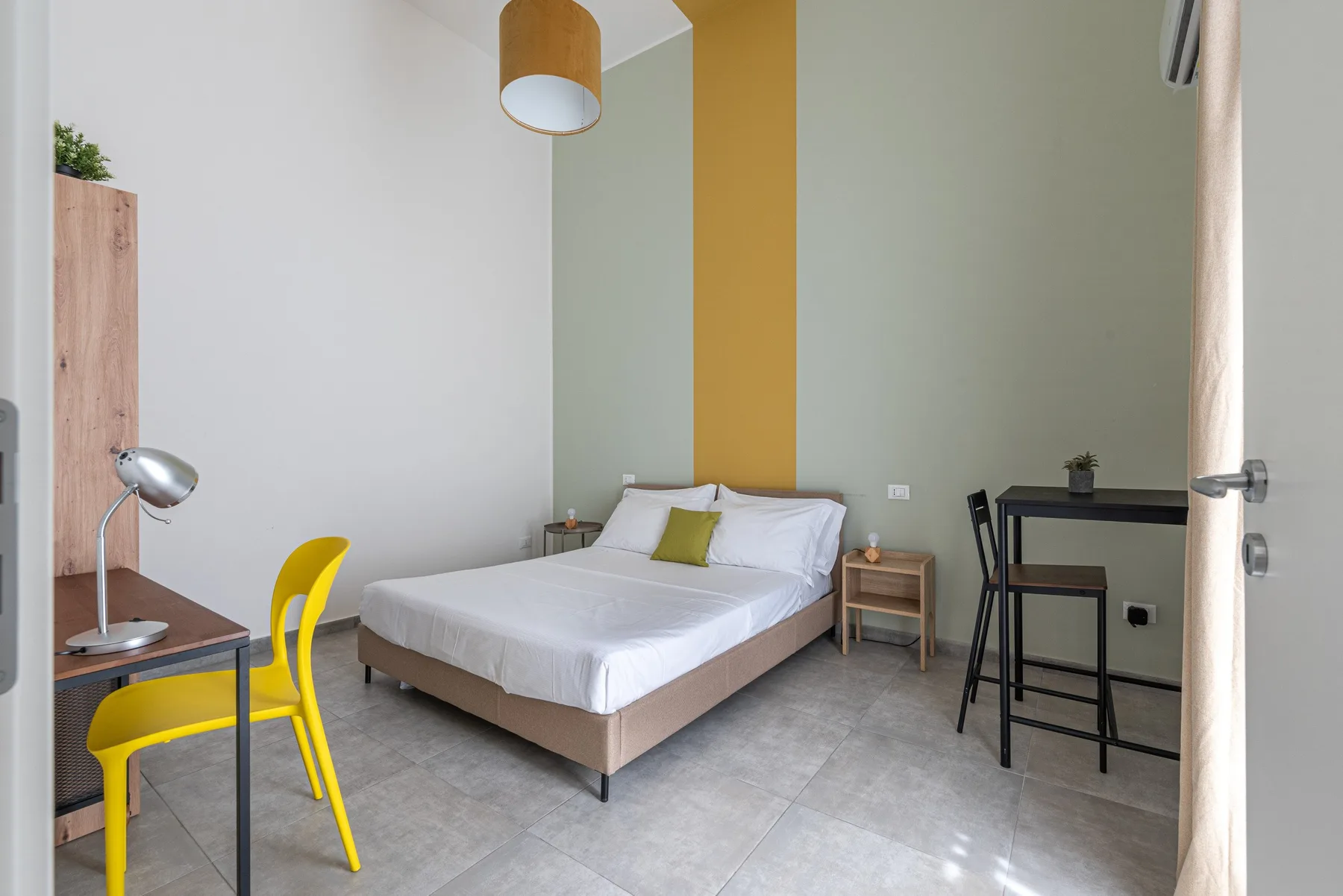 A bedroom with a bed, a desk, and yellow accents.