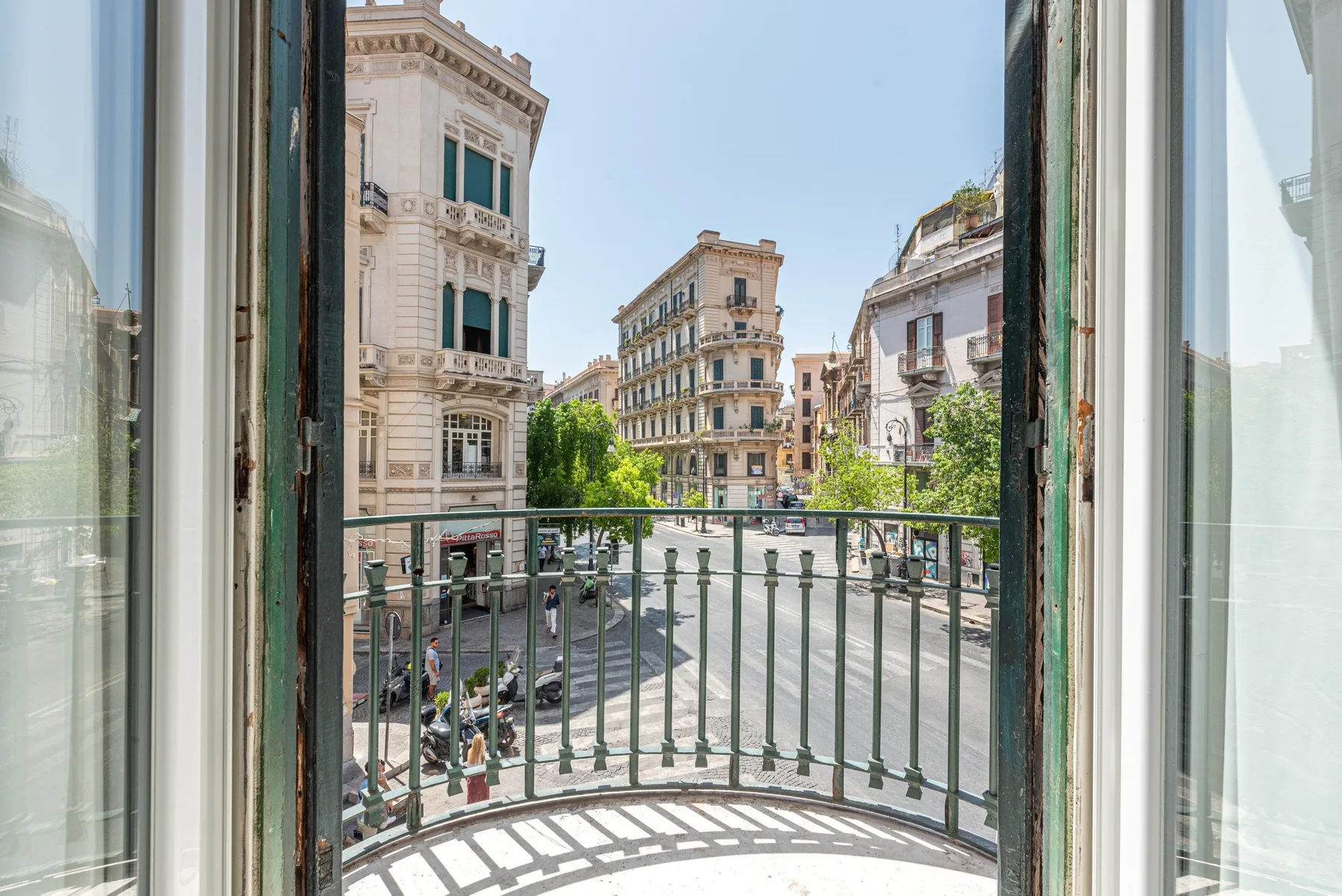 An open balcony overlooks a city street lined with historic-looking buildings.