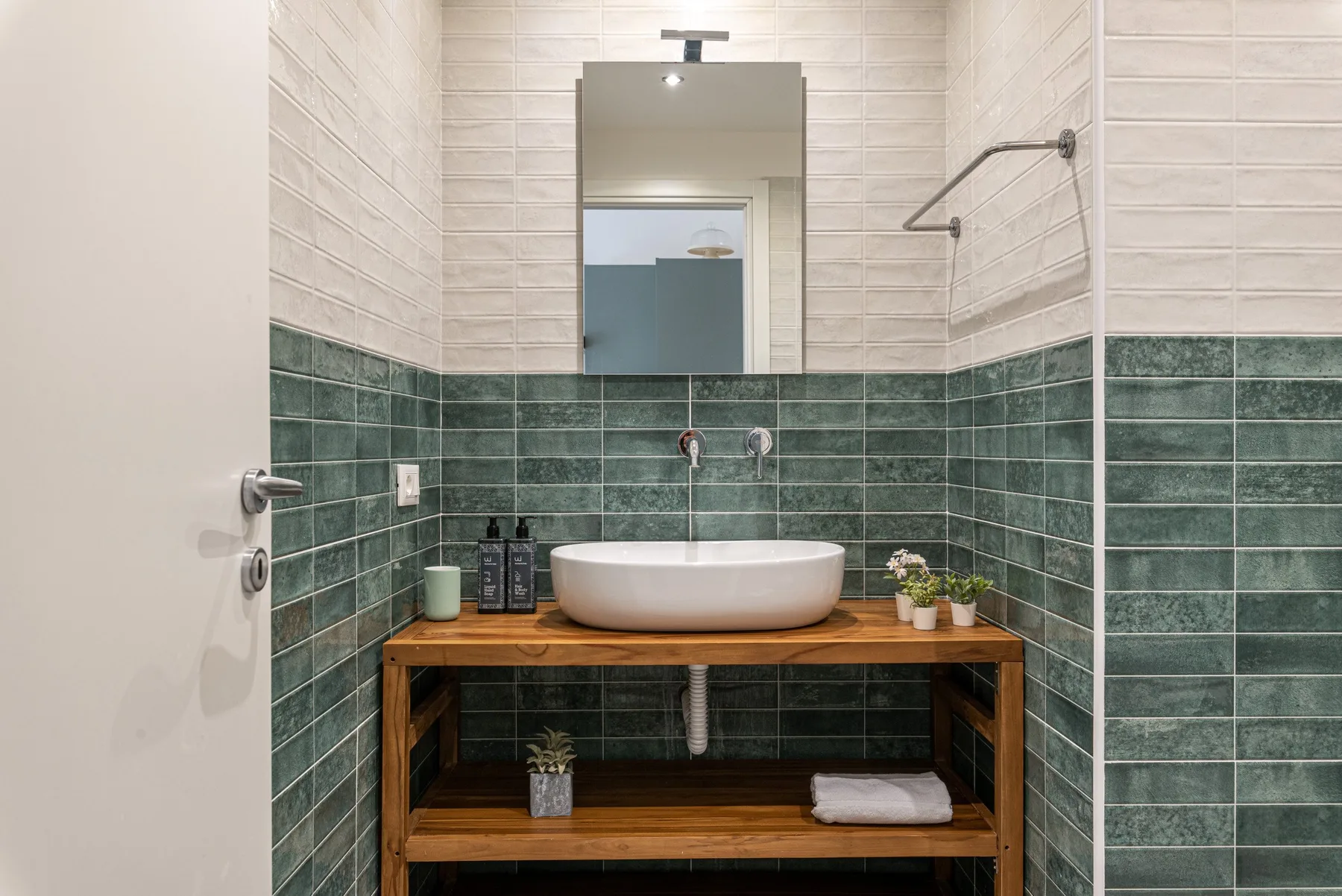 A tiled bathroom with a wooden vanity and a white vessel sink.