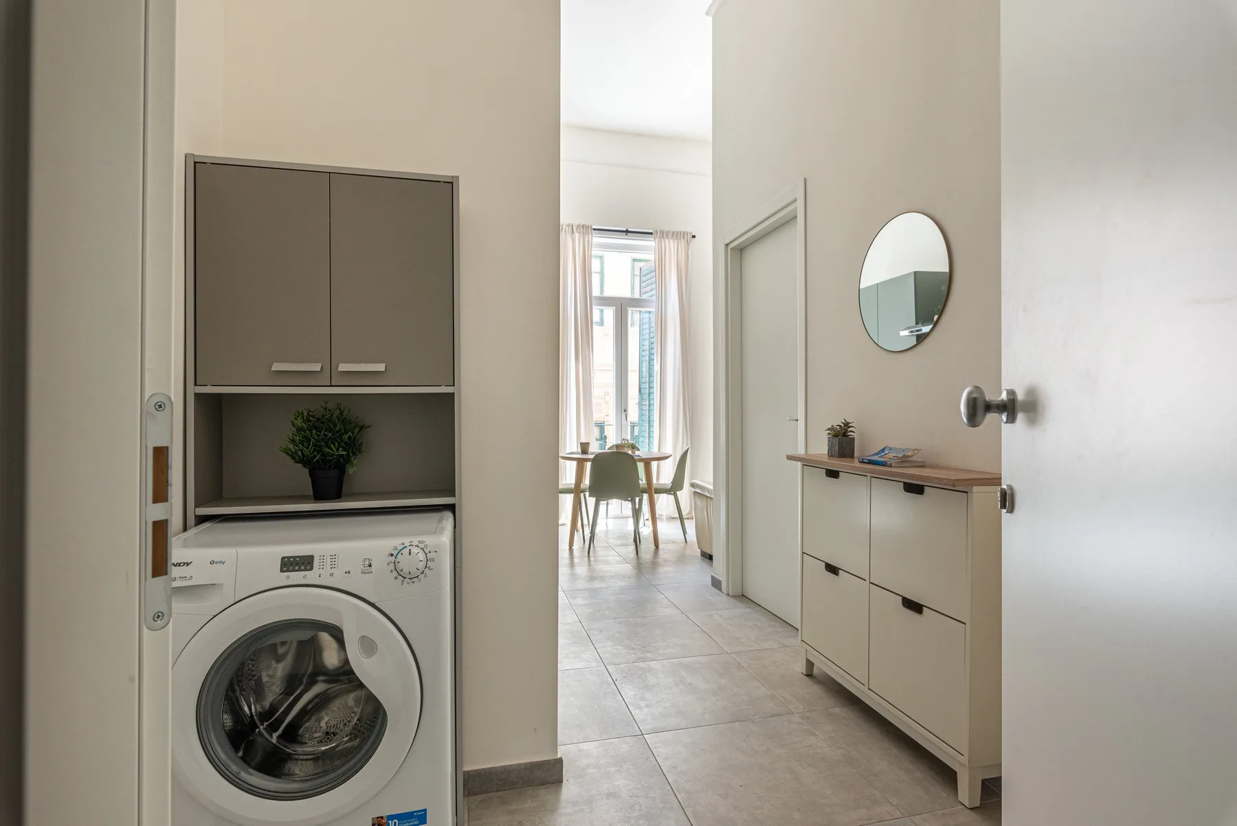 A laundry area opens into a bright dining space with a table and chairs.