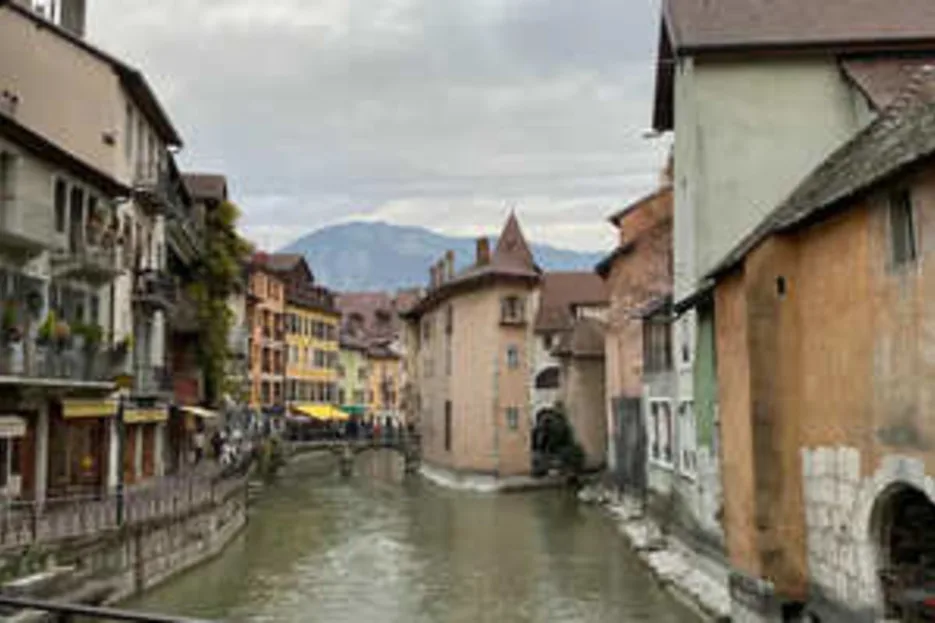 A canal runs through a town street lined with closely spaced buildings.