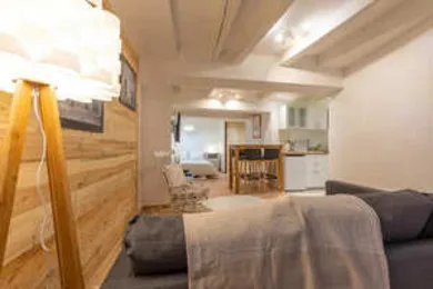 A living area with a sofa faces a dining table and open kitchen.
