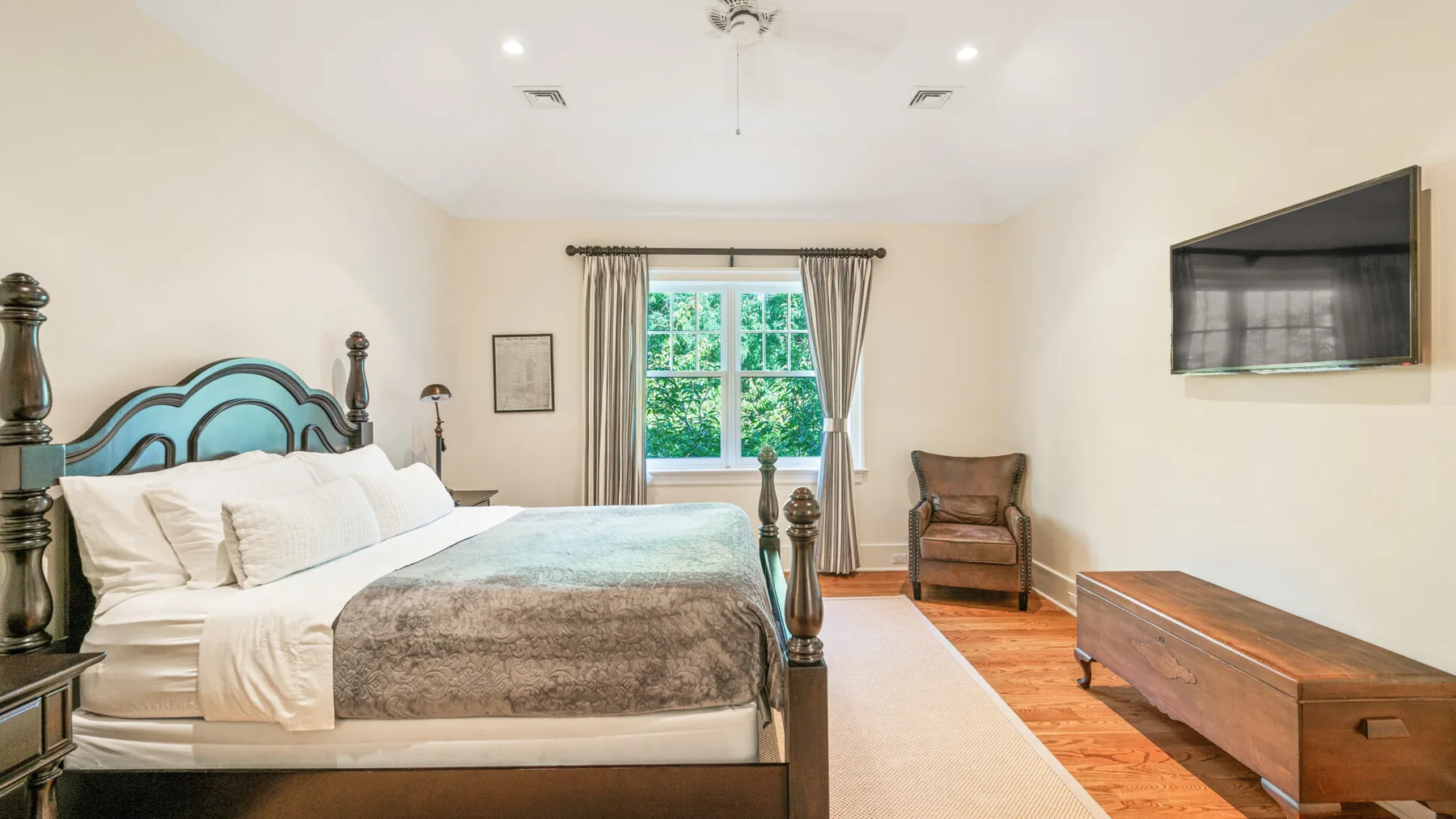 Un dormitorio con una cama, una ventana y un televisor montado en la pared.