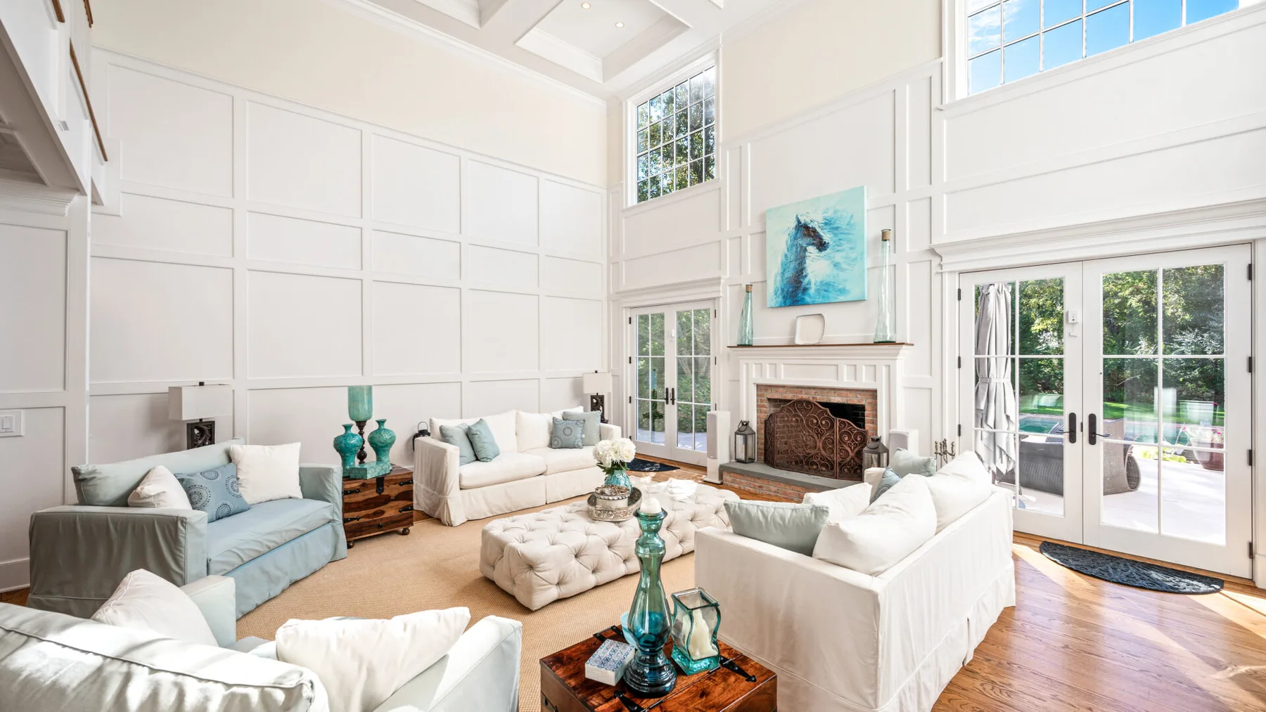 A bright living room with white seating and a fireplace.