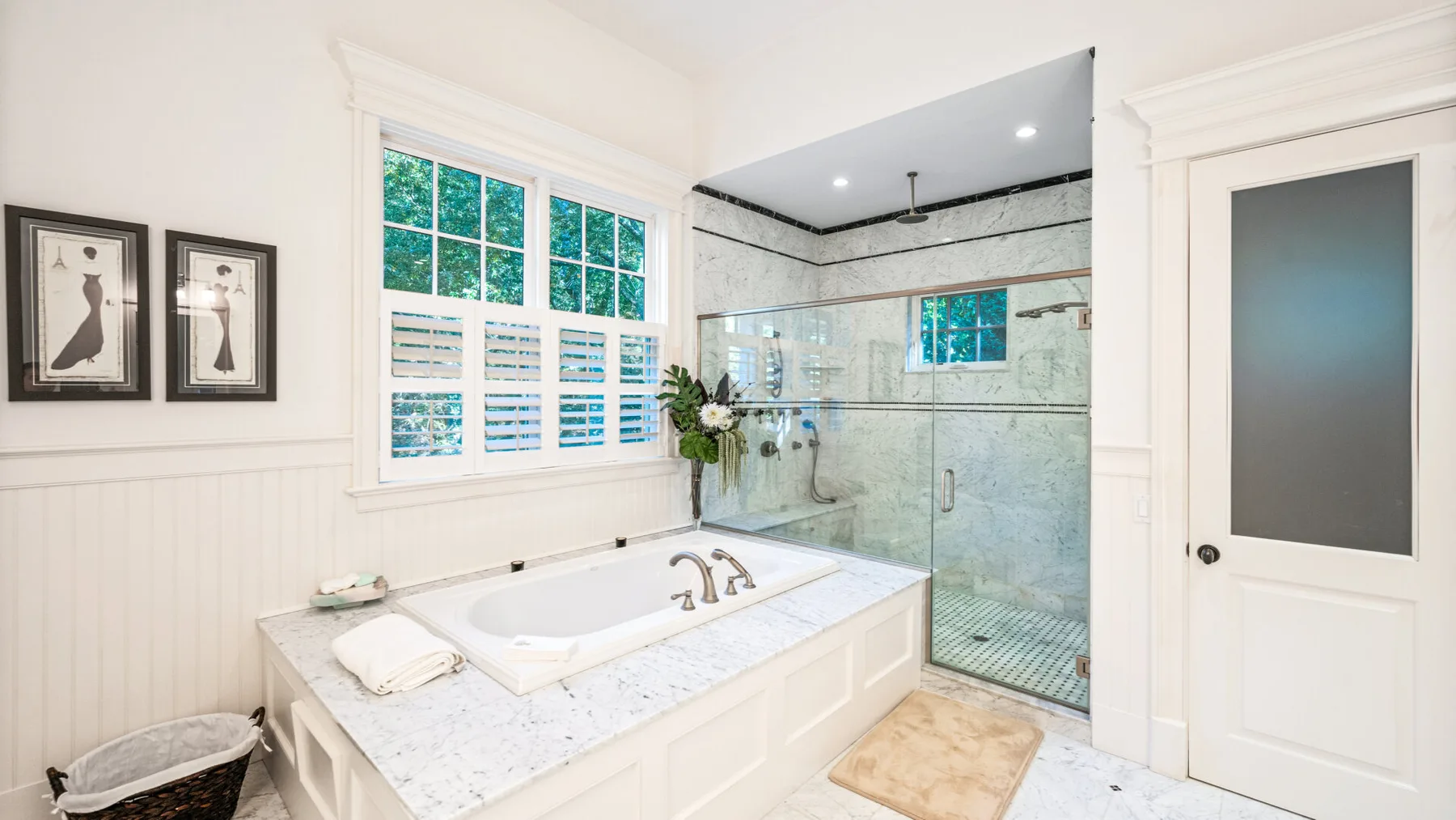Un baño luminoso con lavabo doble y ducha de vidrio.
