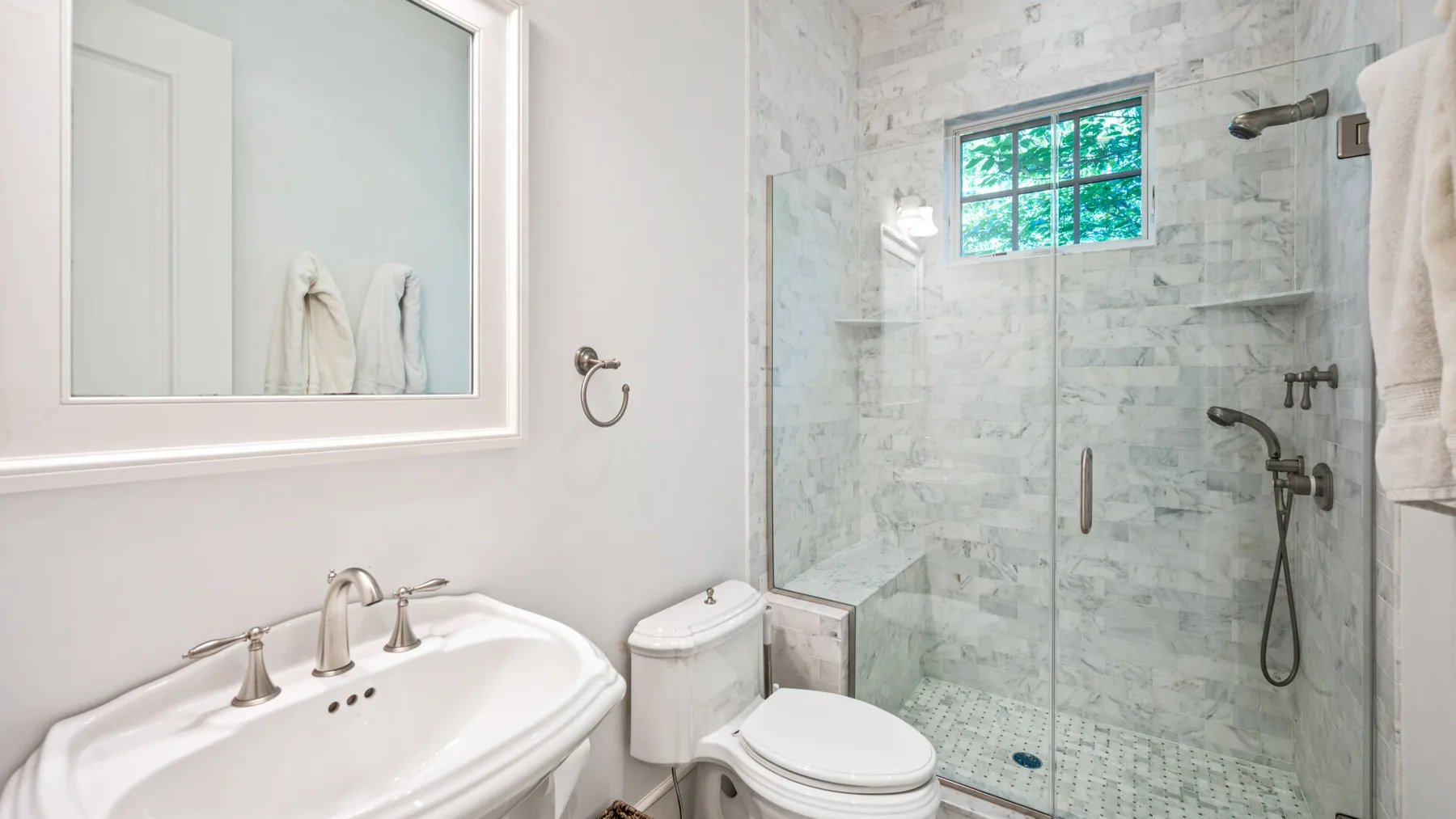 Un baño luminoso con un lavabo blanco y una ducha con mampara de vidrio.