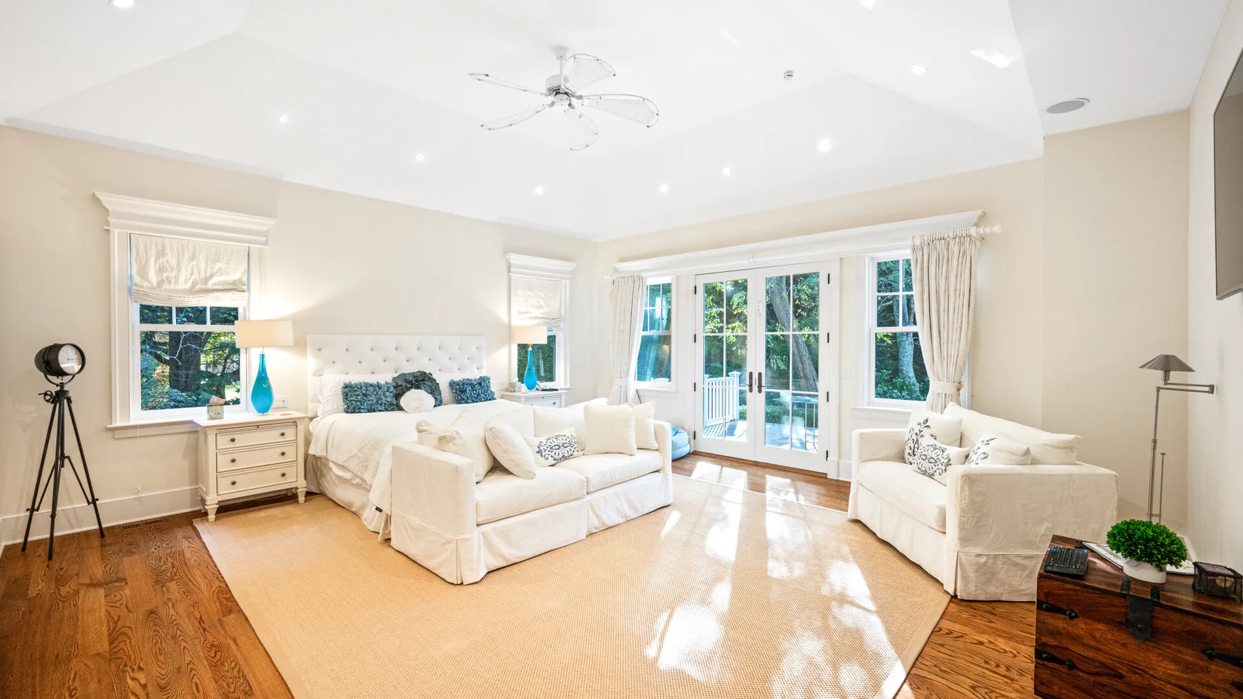 Una sala luminosa con asientos blancos y grandes ventanas que dan a un patio.