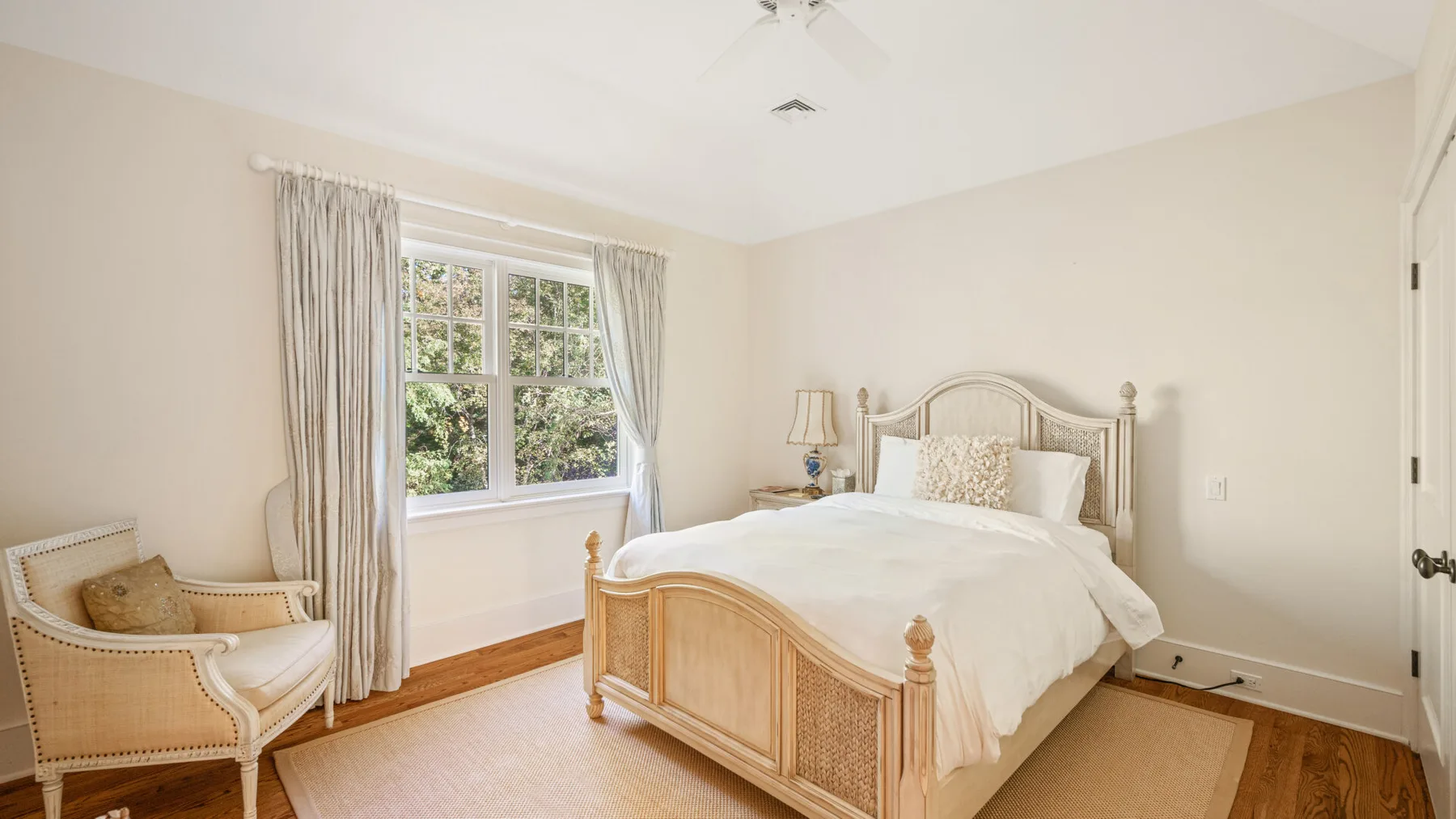 Un dormitorio luminoso con una cama de madera y una gran ventana con cortinas.