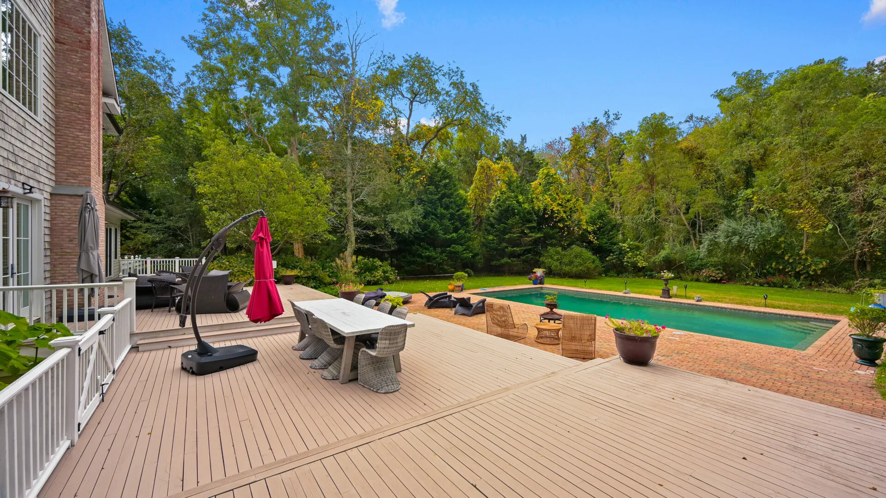 An outdoor deck overlooks a swimming pool and wooded surroundings.