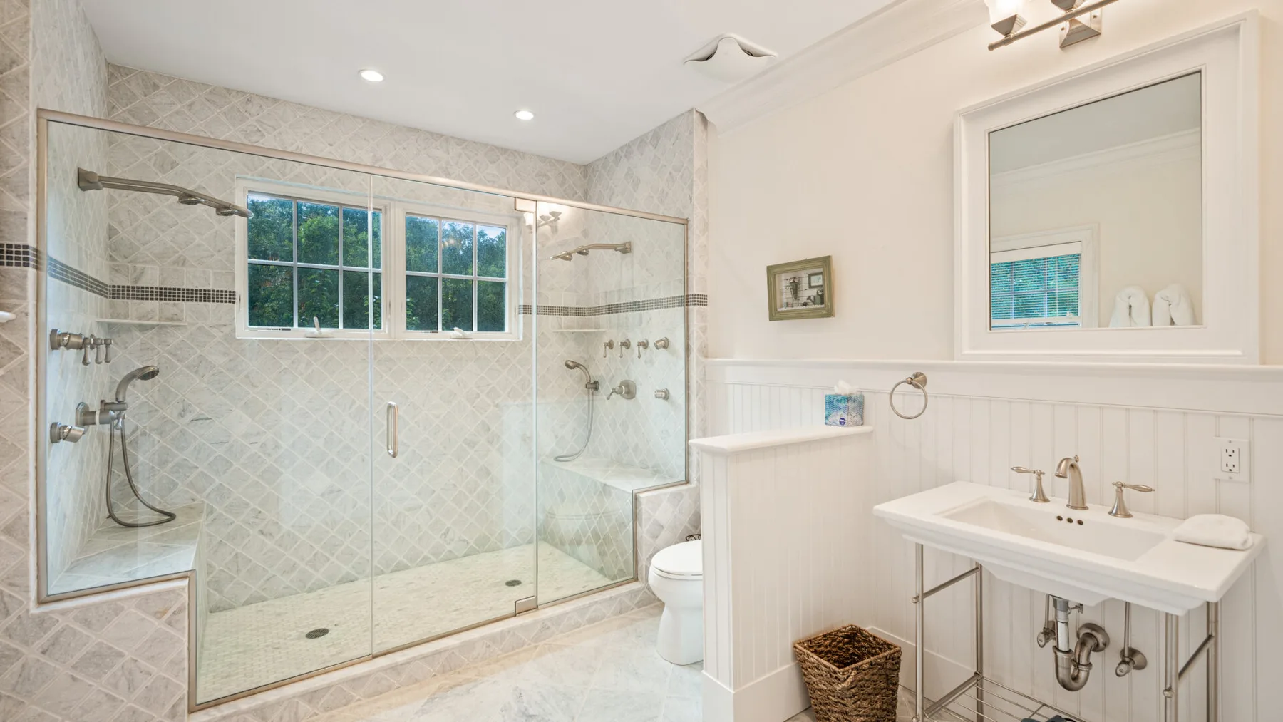 Un baño luminoso con ducha de vidrio y lavabo con mueble.