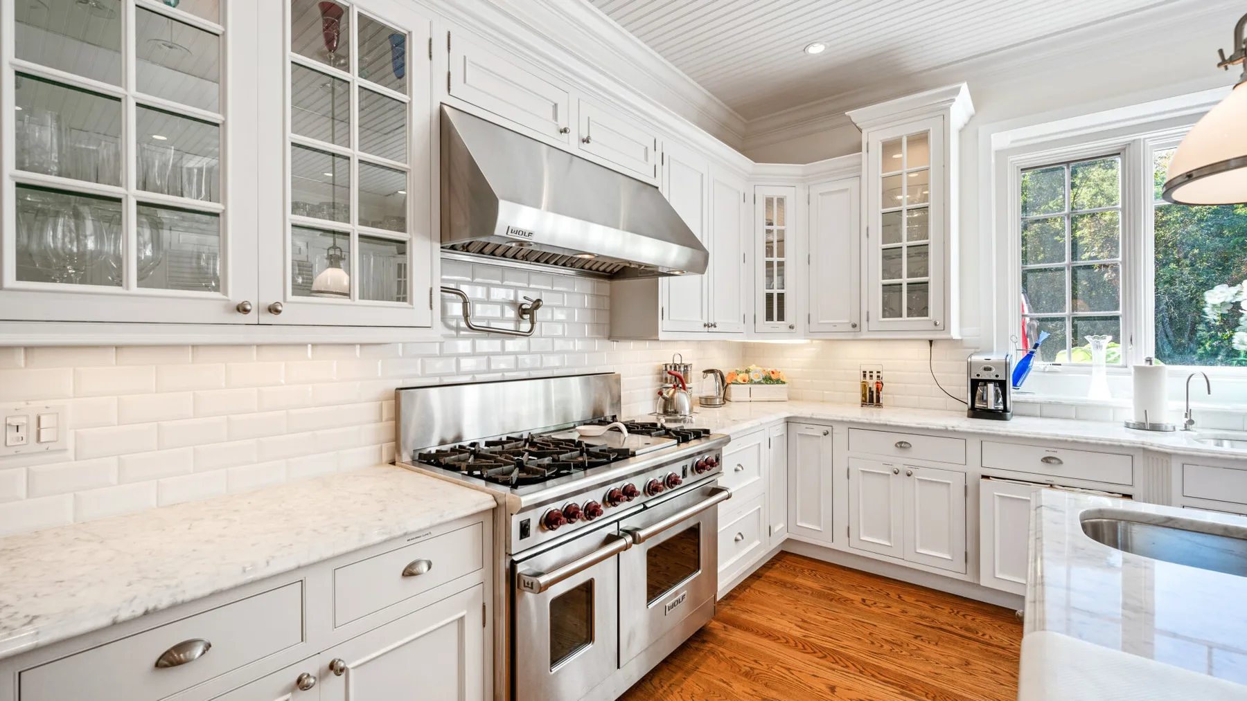 Una cocina luminosa con gabinetes blancos, una estufa y una zona de trabajo central.