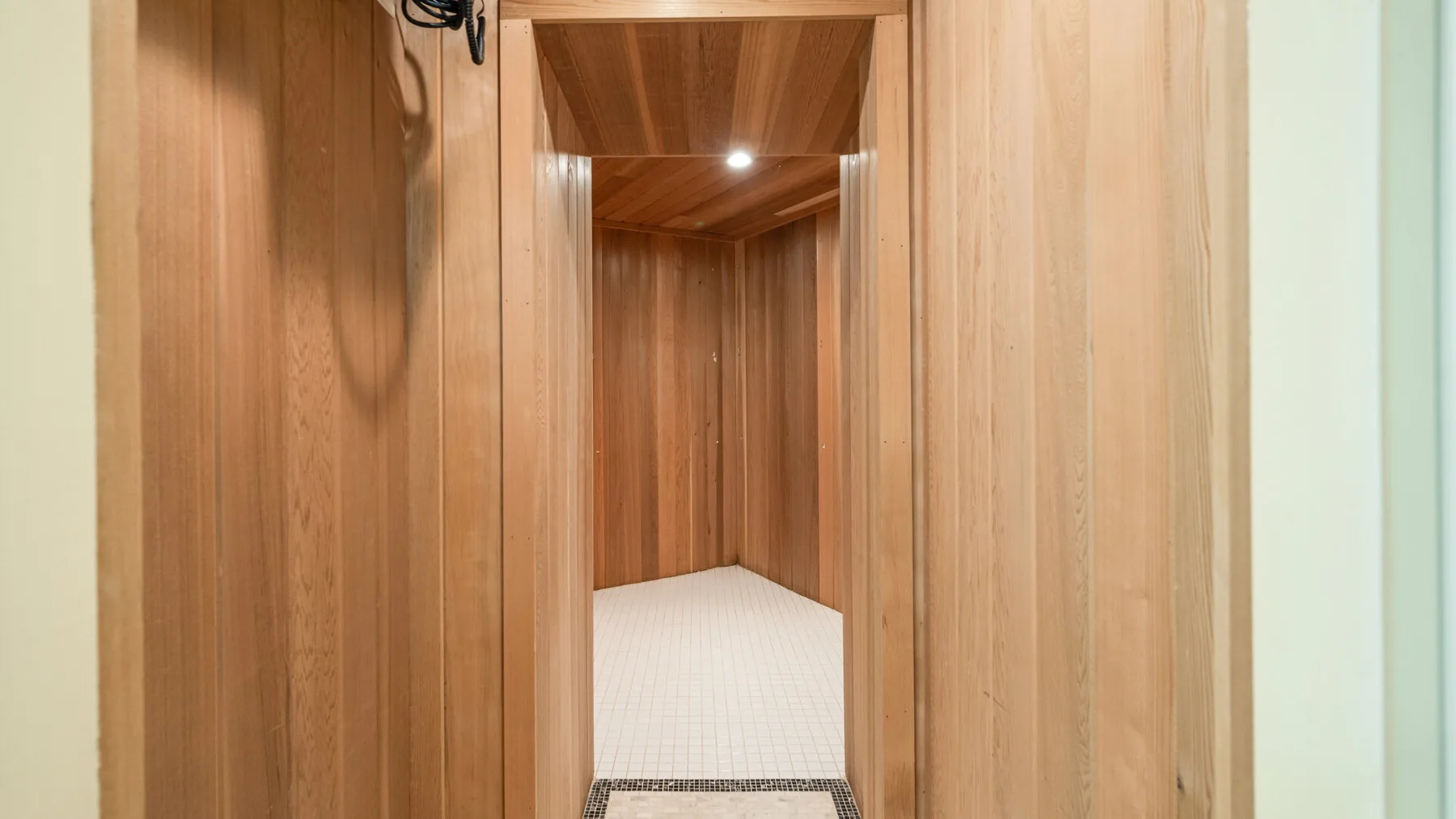 Una habitación revestida de madera, con techo bajo y suelo claro.