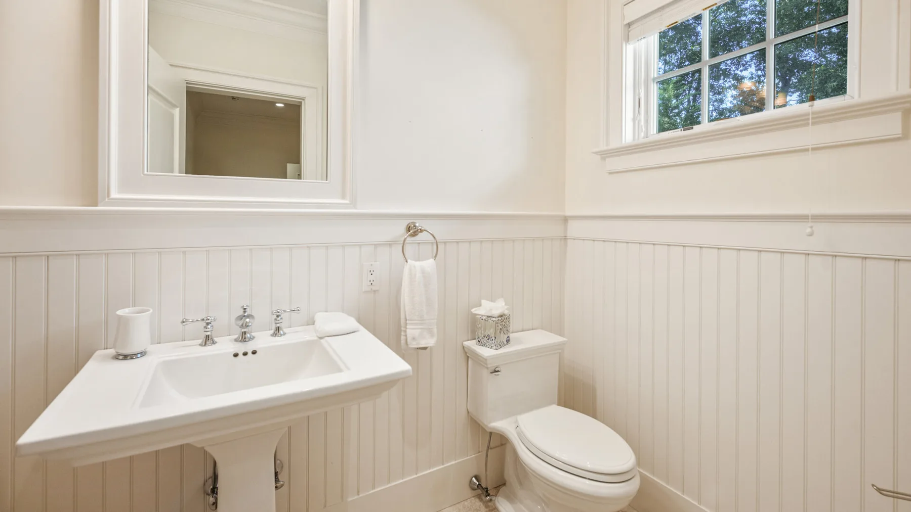 Un baño luminoso con lavabo, inodoro y ventana.