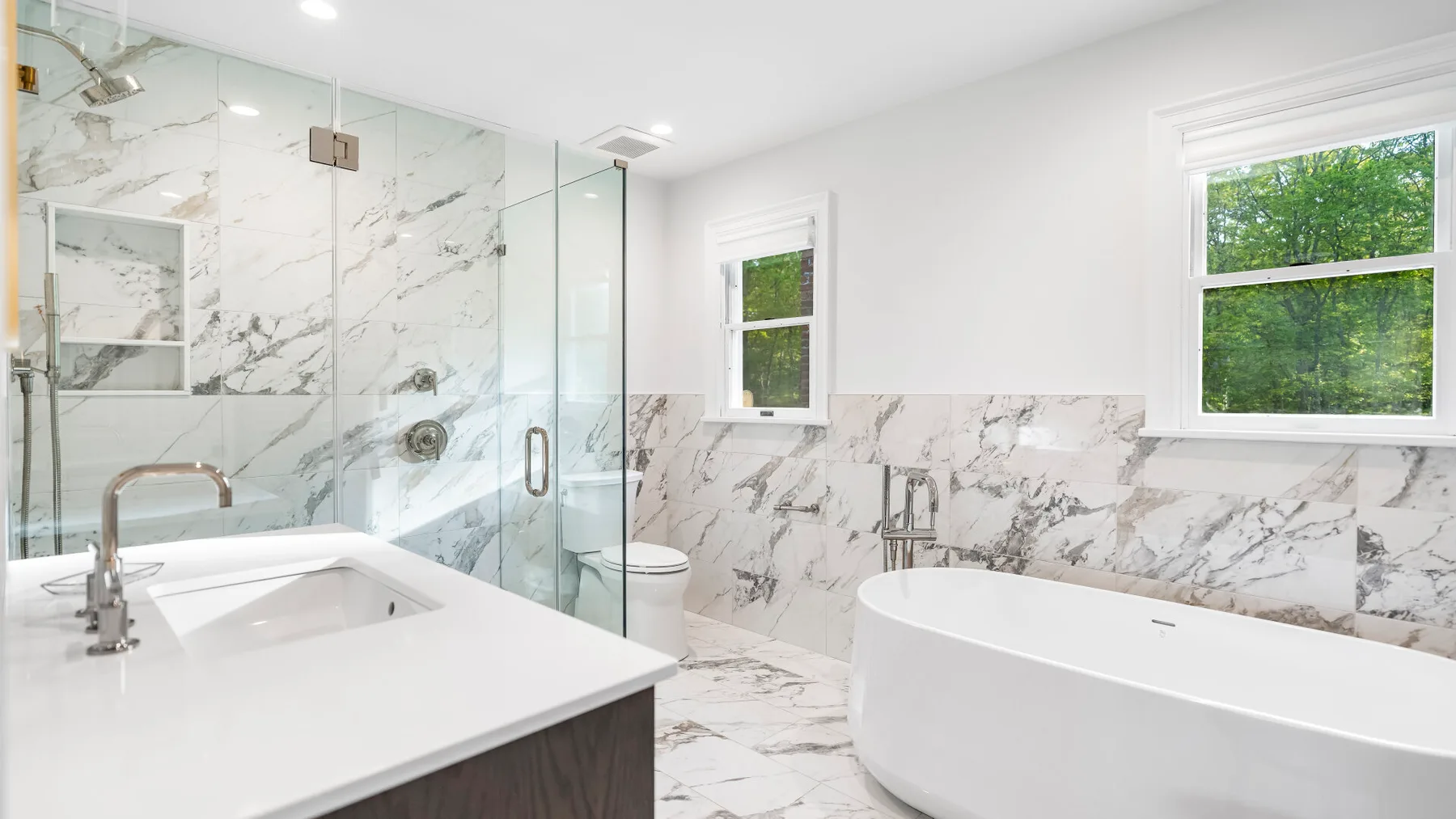 Un baño luminoso con bañera exenta y ducha de vidrio.
