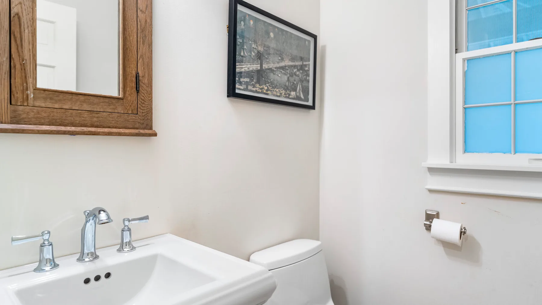 Un baño con lavabo e inodoro junto a una ventana.