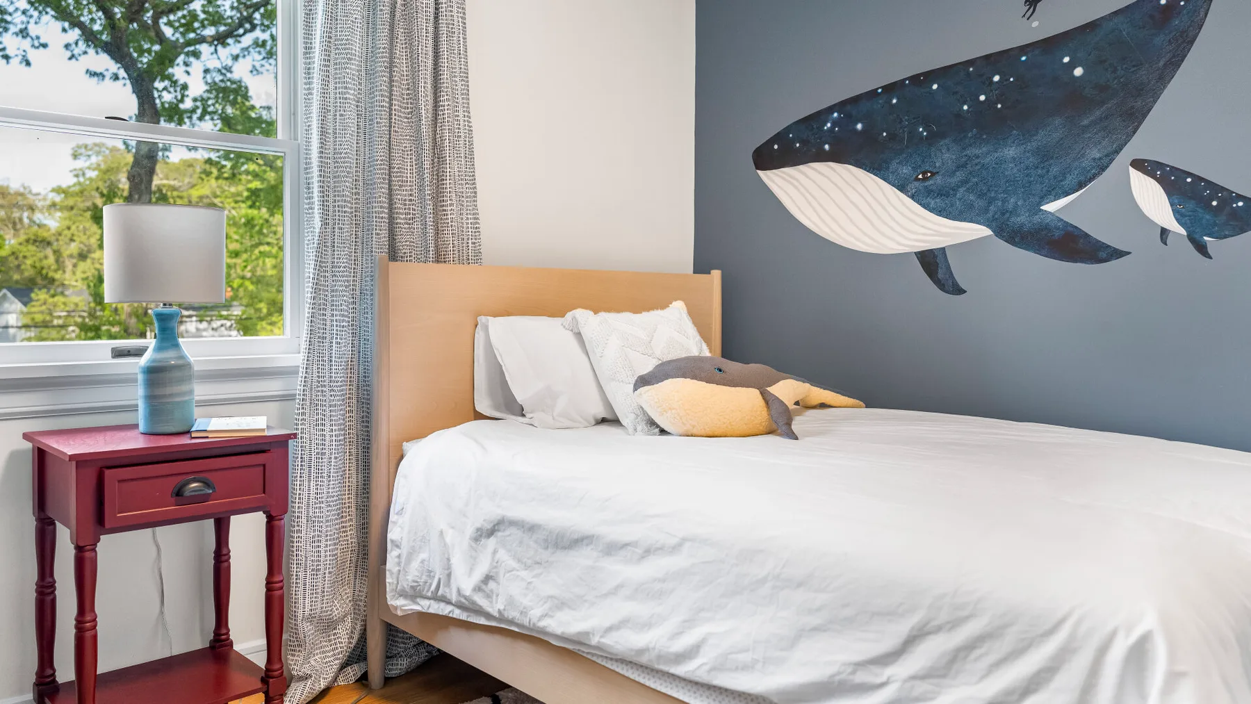Un dormitorio con una cama y murales de ballenas en la pared.