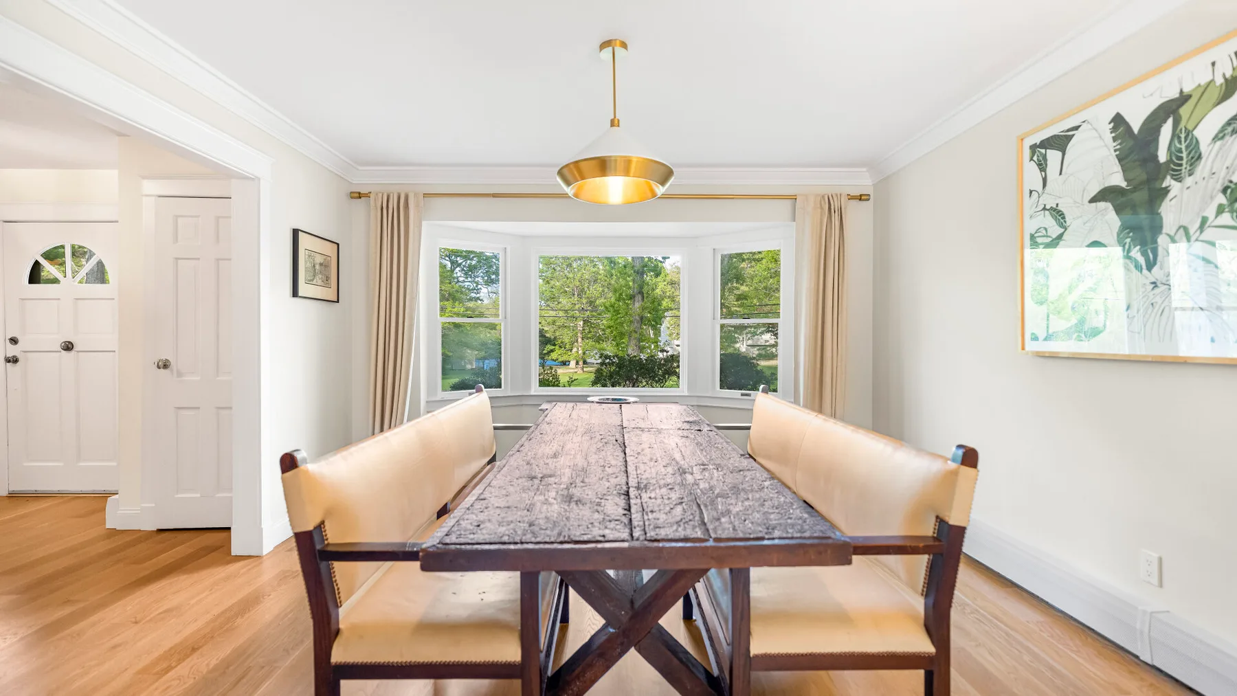 Un comedor con una mesa larga y grandes ventanas con vistas a zonas verdes.