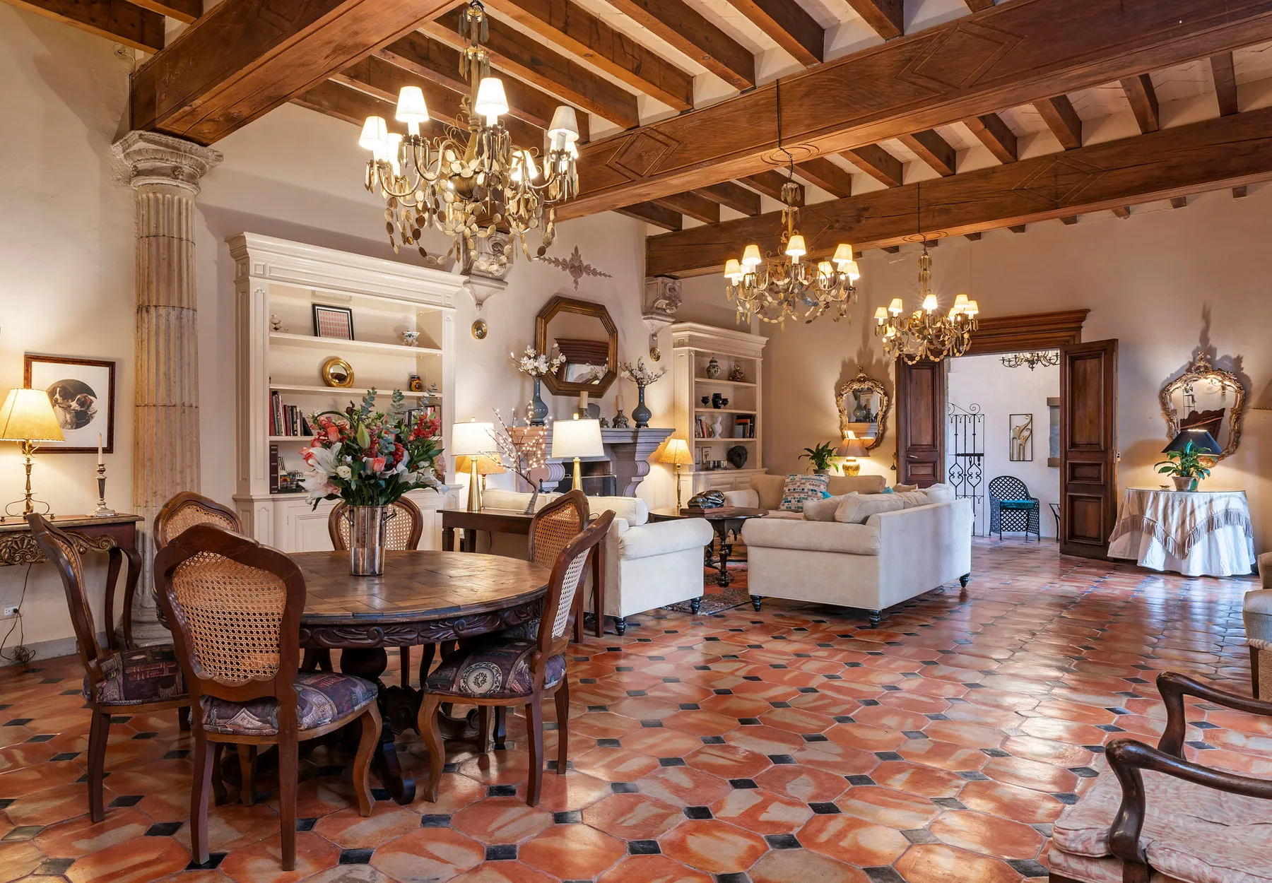 A spacious living and dining room with exposed wooden beams and seating.