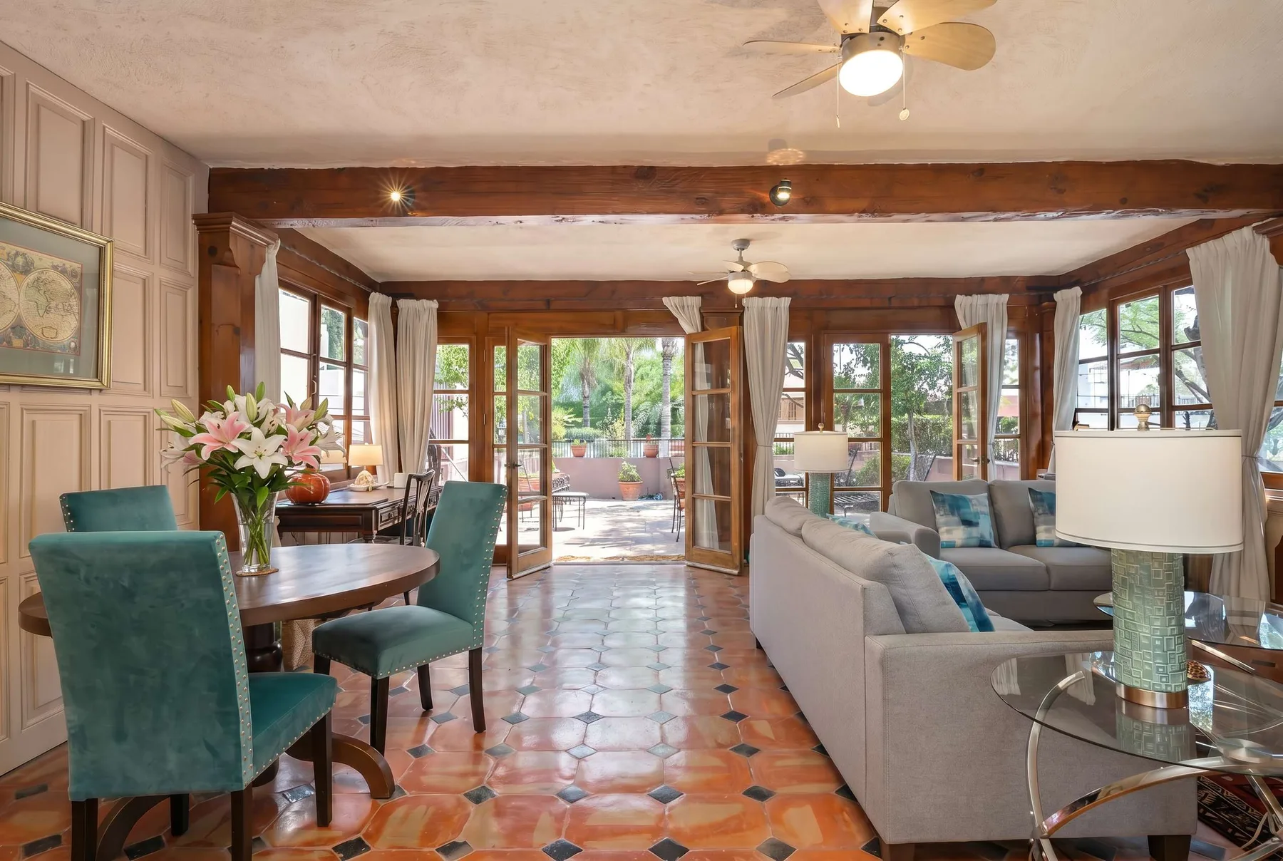 A bright living and dining area opens onto a garden through large windows and doors.