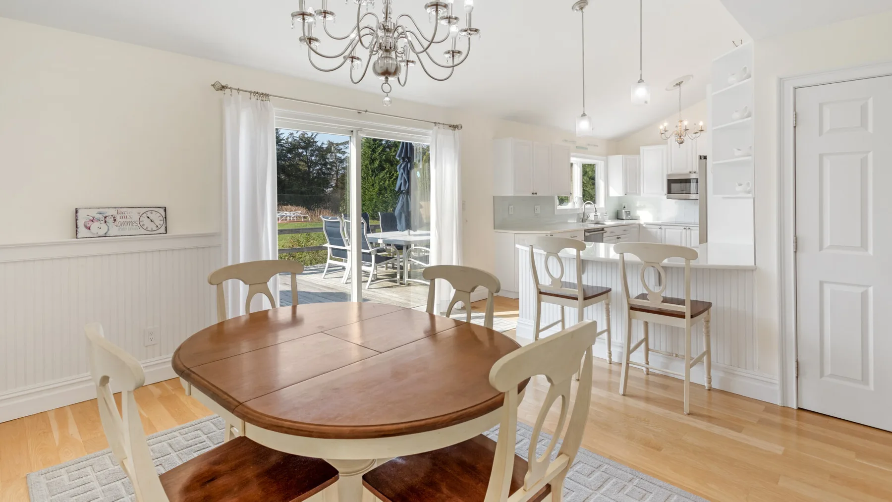 Un comedor con mesa de madera y sillas junto a una cocina abierta y luminosa.