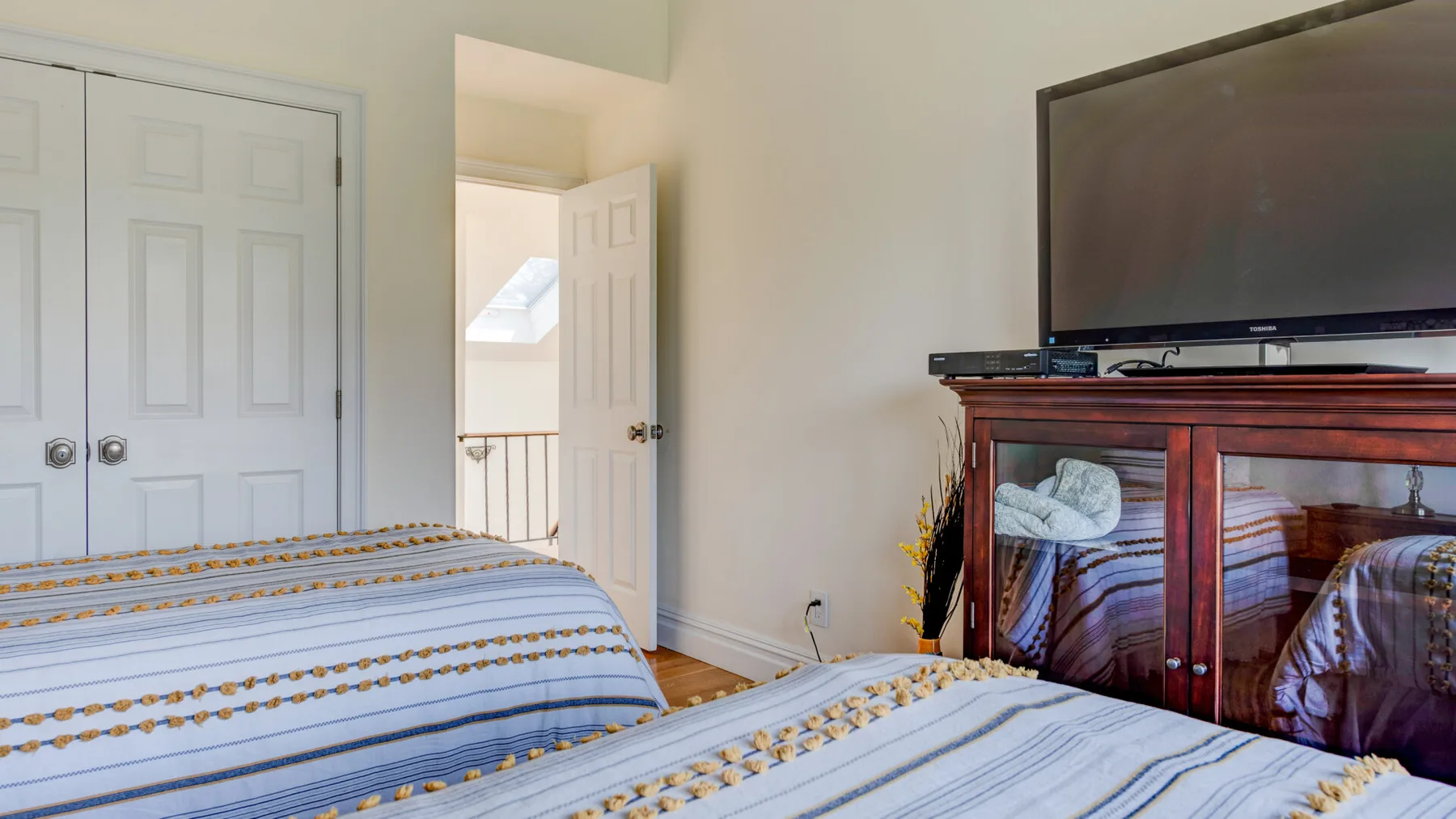 Un dormitorio con una cama bien tendida y un televisor sobre un mueble de madera.