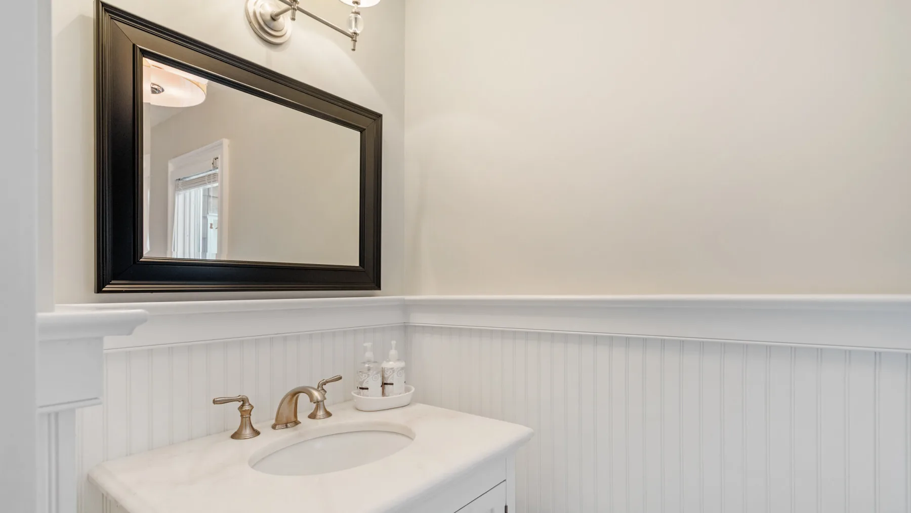 Un lavabo de baño con un espejo grande enmarcado.