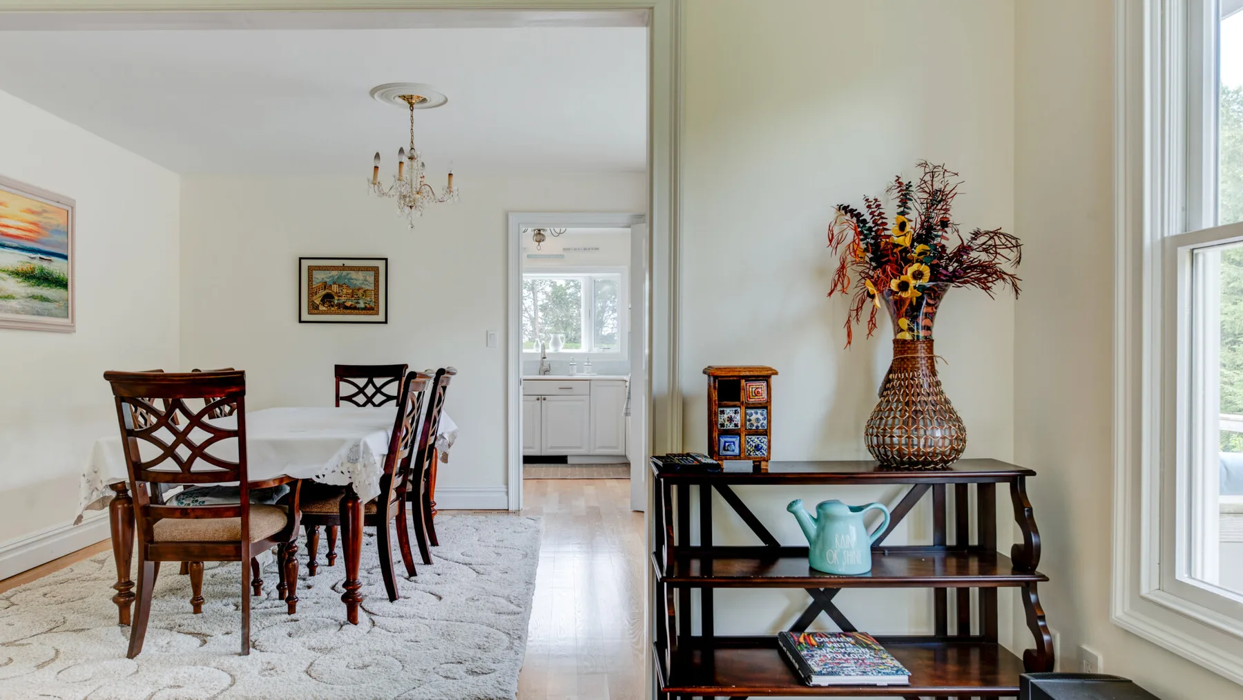 Un comedor luminoso con mesa, sillas y una estantería junto a la ventana.