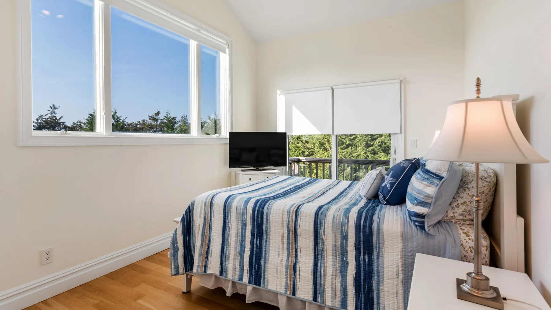Un dormitorio luminoso con una cama cubierta con ropa de cama a rayas azules y blancas.