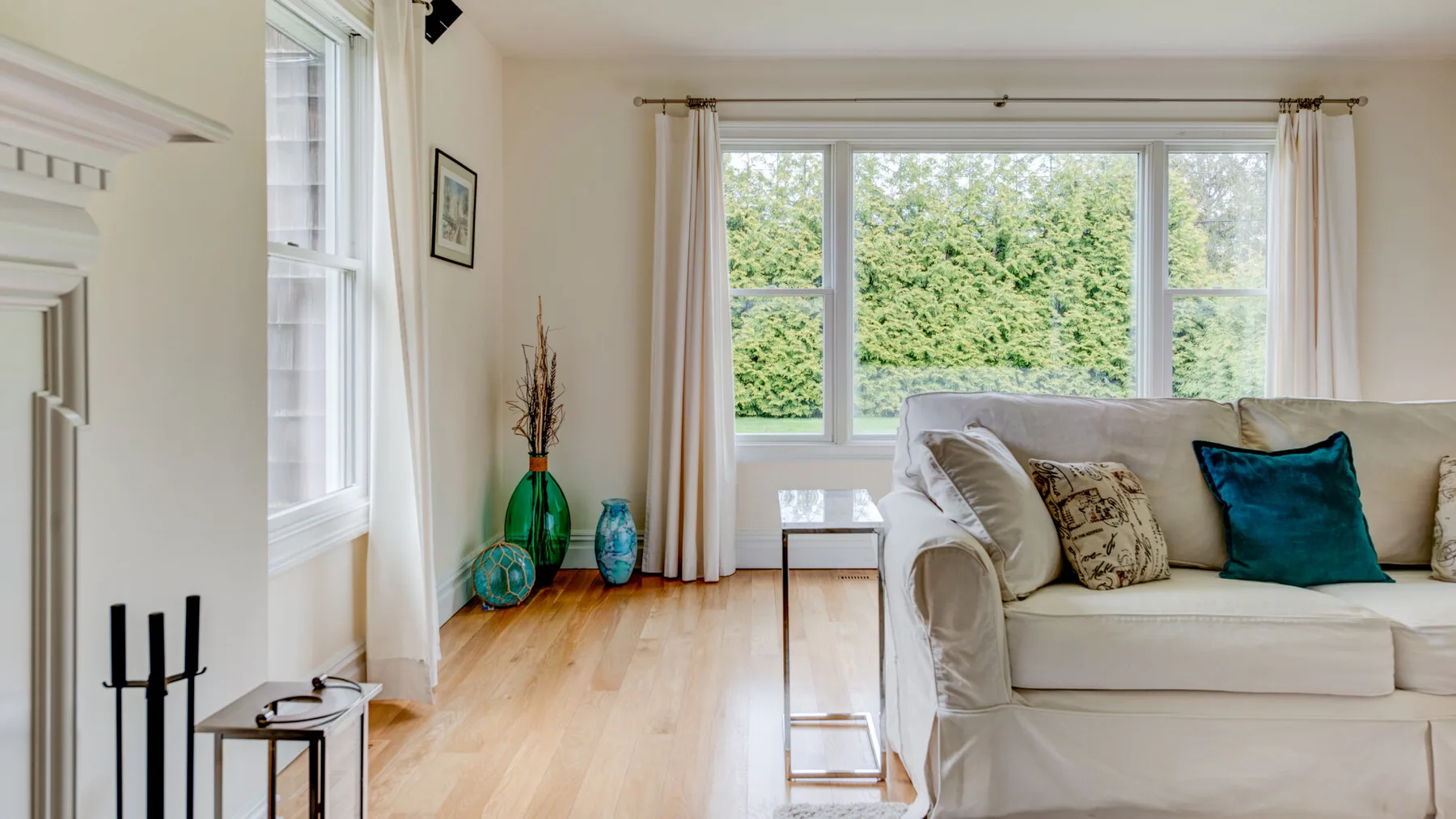 Una sala luminosa con un sofá junto a grandes ventanas con vistas a la vegetación.