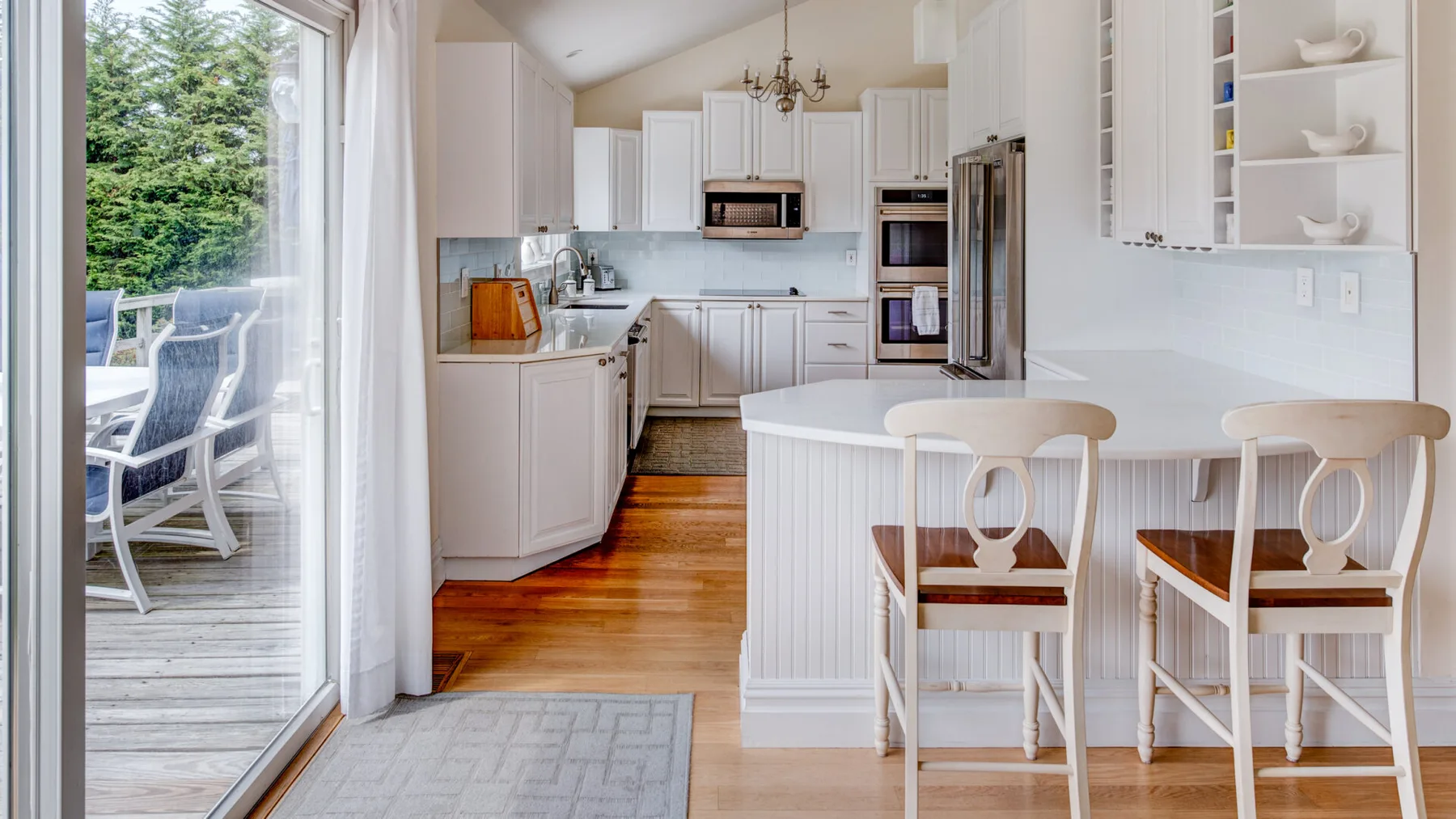 Una cocina luminosa con una isla central, gabinetes blancos y suelo de madera.
