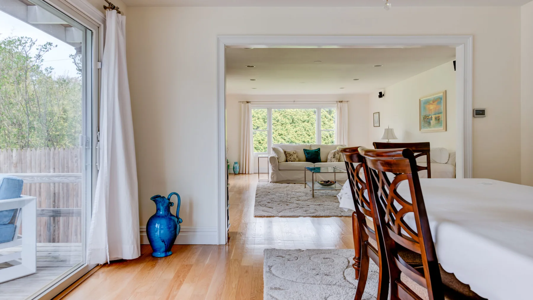 An open dining area leads into a bright living room with large windows.