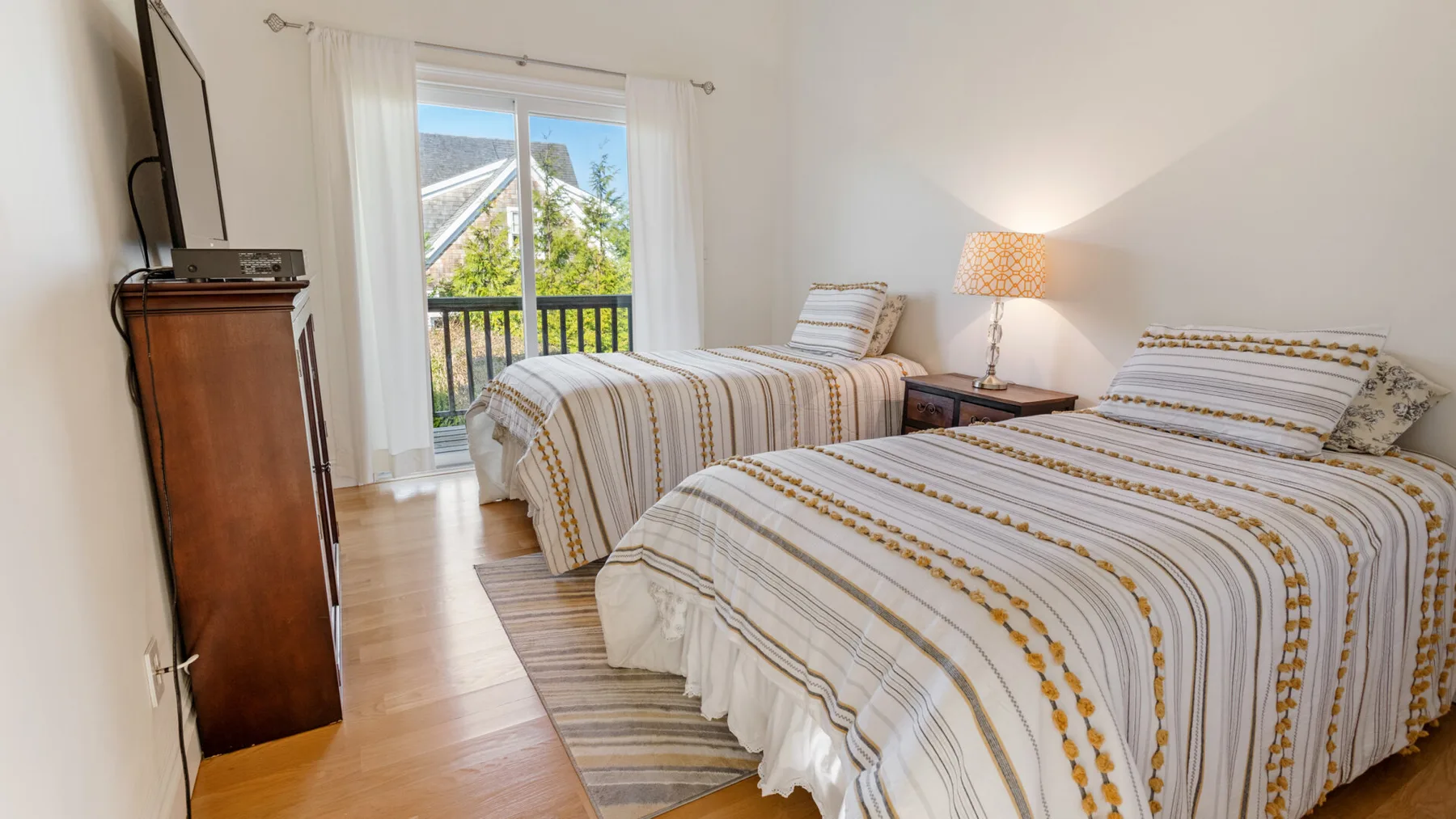 Un dormitorio con dos camas vestidas con ropa de rayas y una puerta al balcón.
