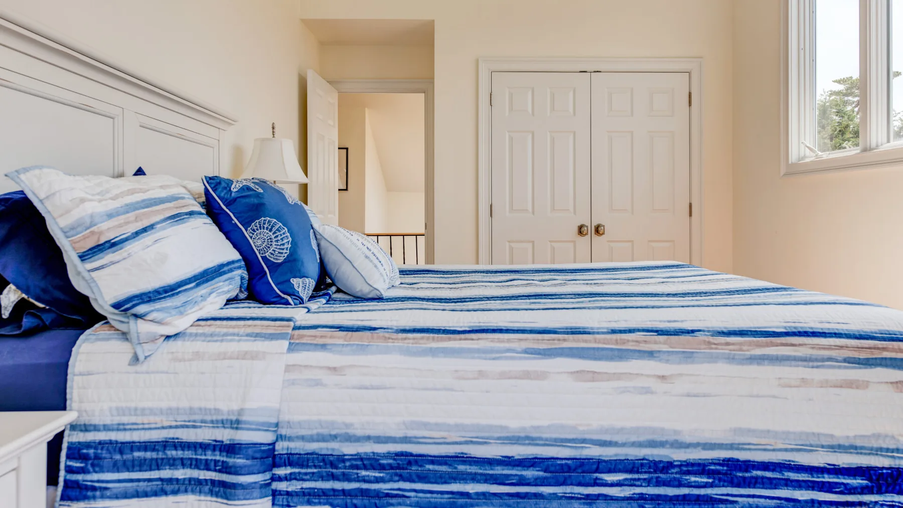 Un dormitorio con ropa de cama a rayas azules y blancas y una ventana.